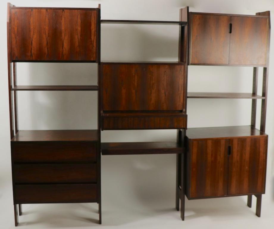Nice Danish modern wall unit, having floating storage cabinets, a drop front desk, and pullout / pull-out shelf. Executed in rosewood veneer, the rich dark finish makes this an especially beautiful example. The cabinets and desk can be arranged to