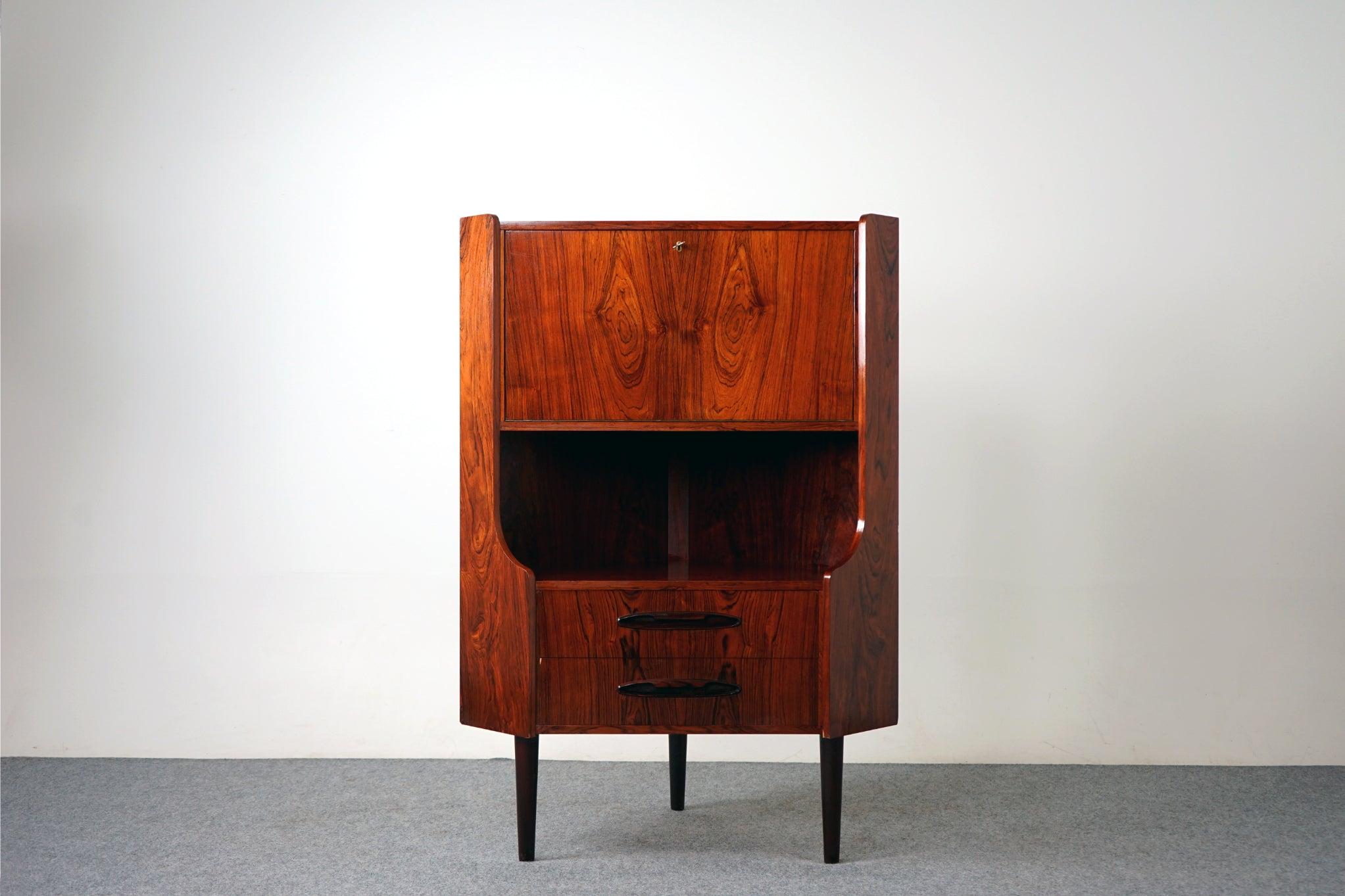 Rosewood corner cabinet, circa 1960's. Top section drops down to reveal interior shelving, bottom section consists of two drawers with dovetail construction. Back of piece shows 