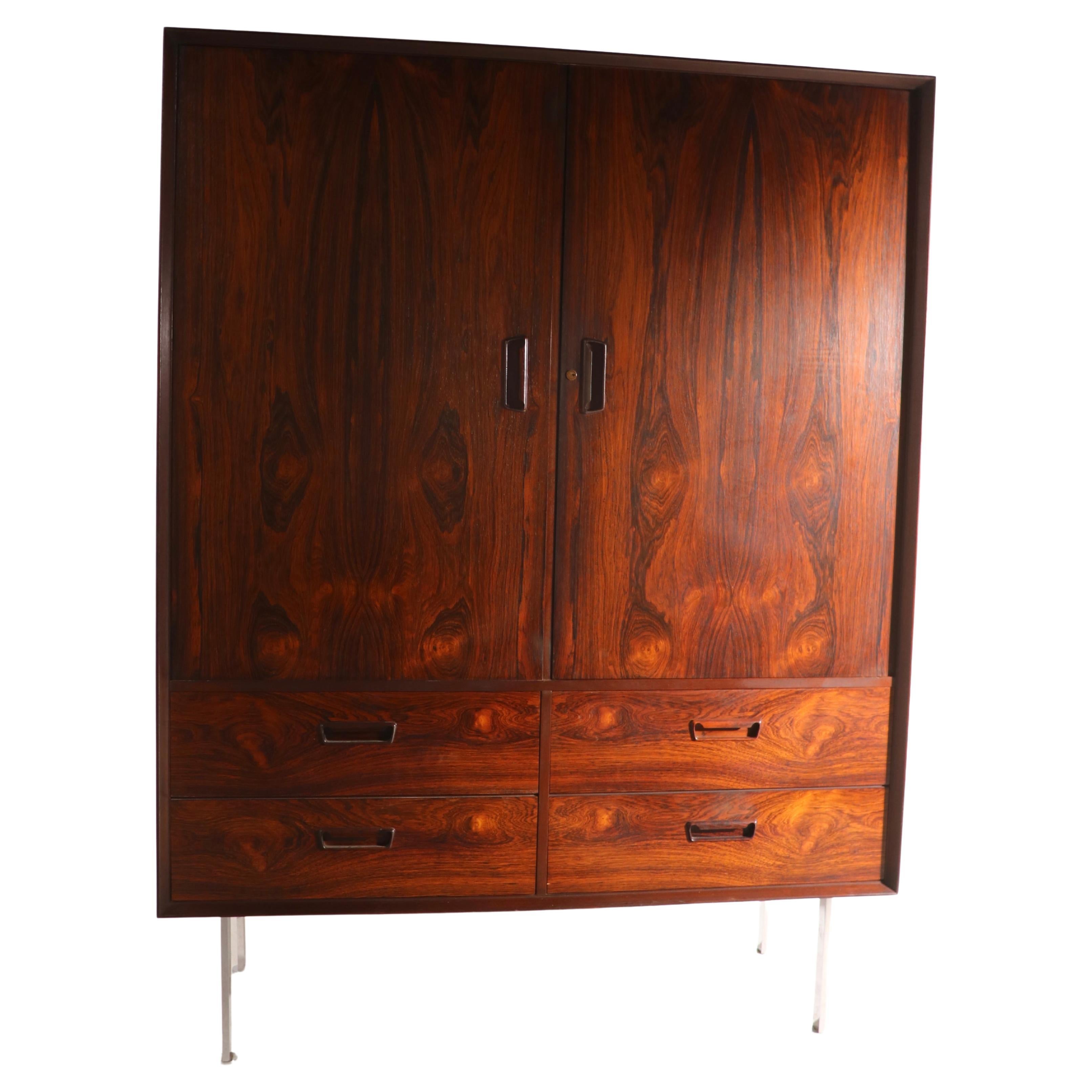 Spectacular rosewood chifforobe on bright come legs. The cabinet features a vibrant rosewood veneer case with two large doors, which open to reveal interior drawers, and shelved storage space. Underneath the doors are two additional drawers,