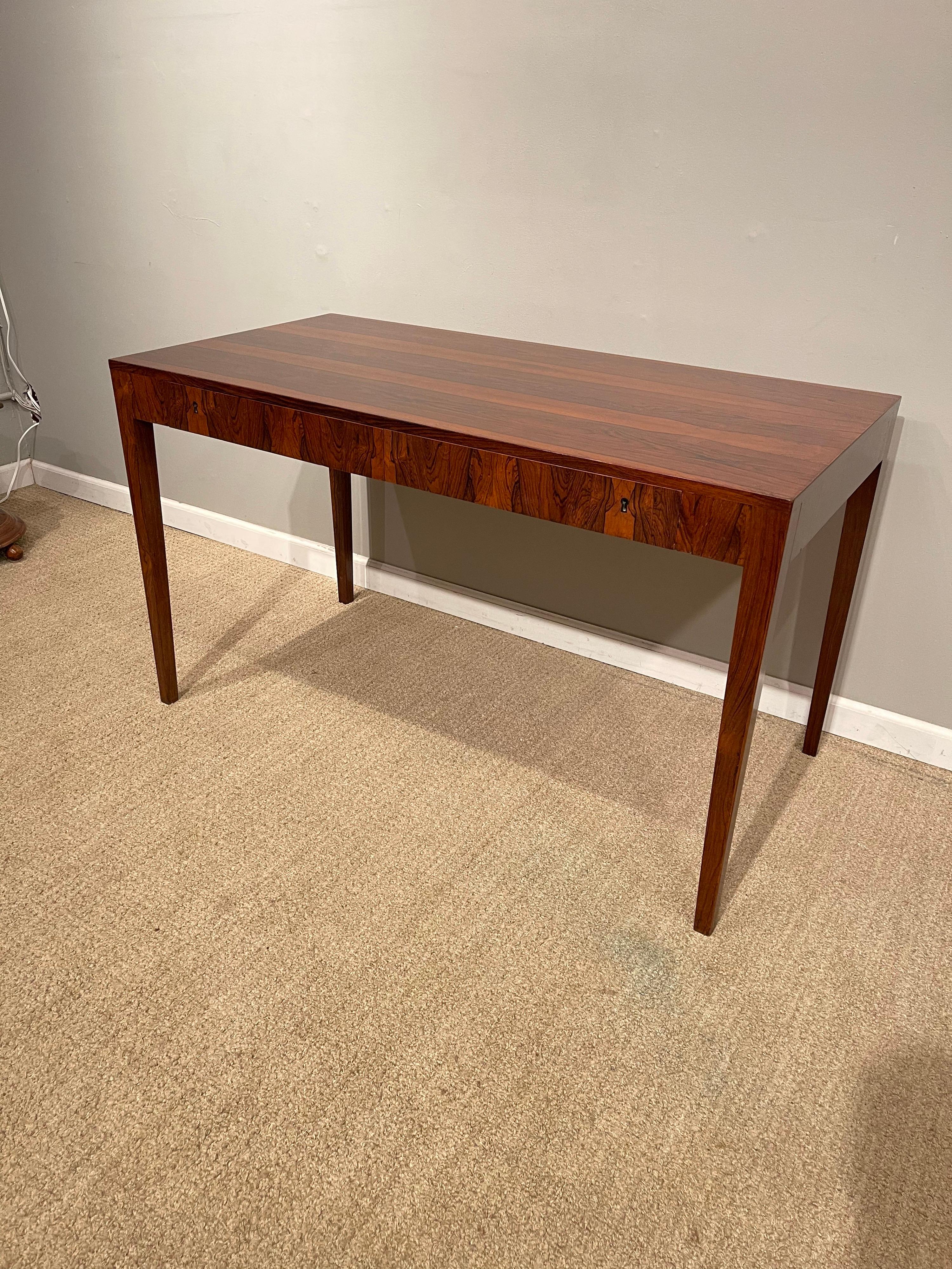A Rosewood Danish modern writing table, by Riis Antonsen with 2 drawers, 1 key.