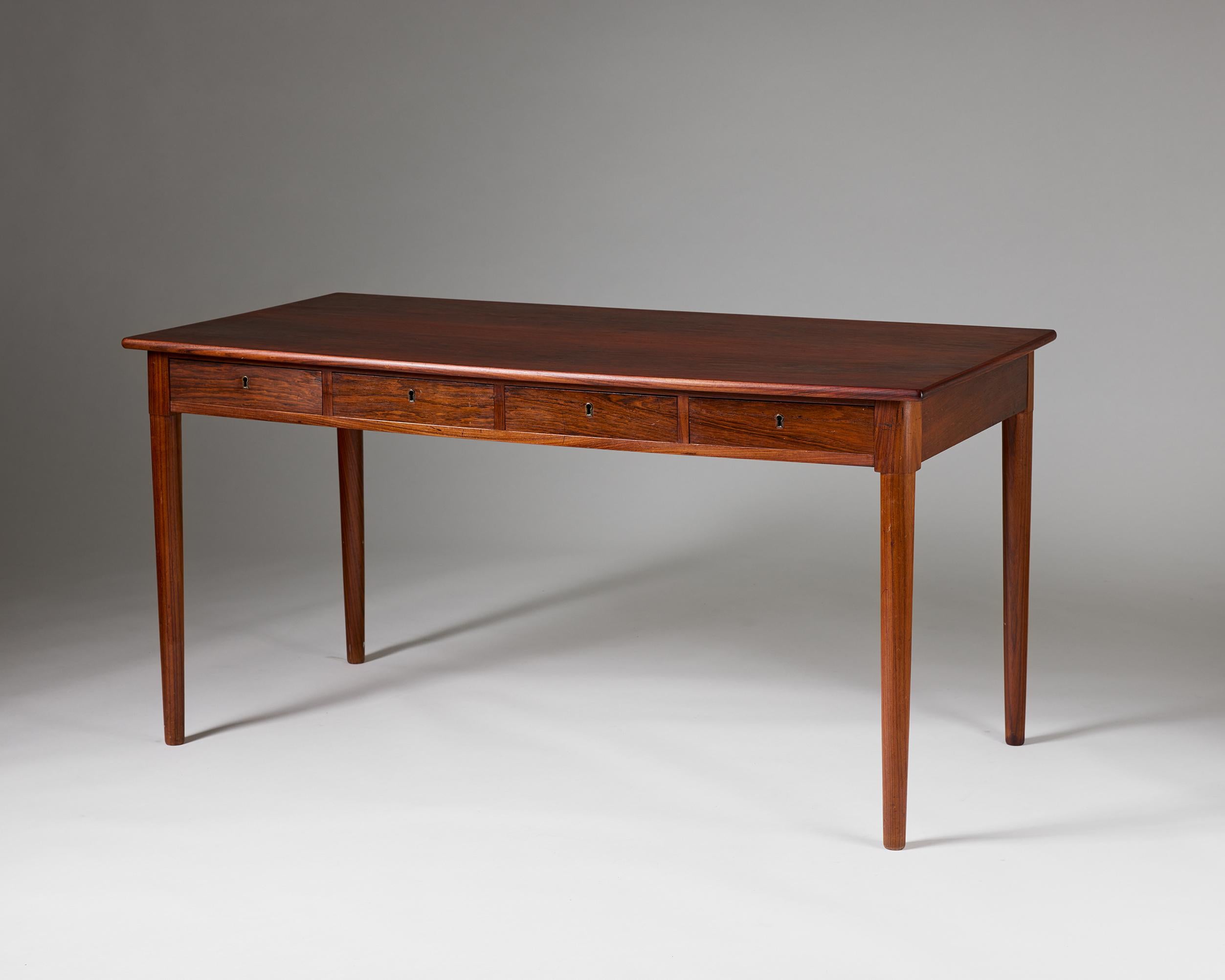 Questa scrivania scandinava di metà secolo combina una raffinata abilità artigianale con un senso di semplicità senza tempo che definisce il meglio del design nordico. Realizzato in legno di palissandro con una ricca venatura, il pezzo presenta un