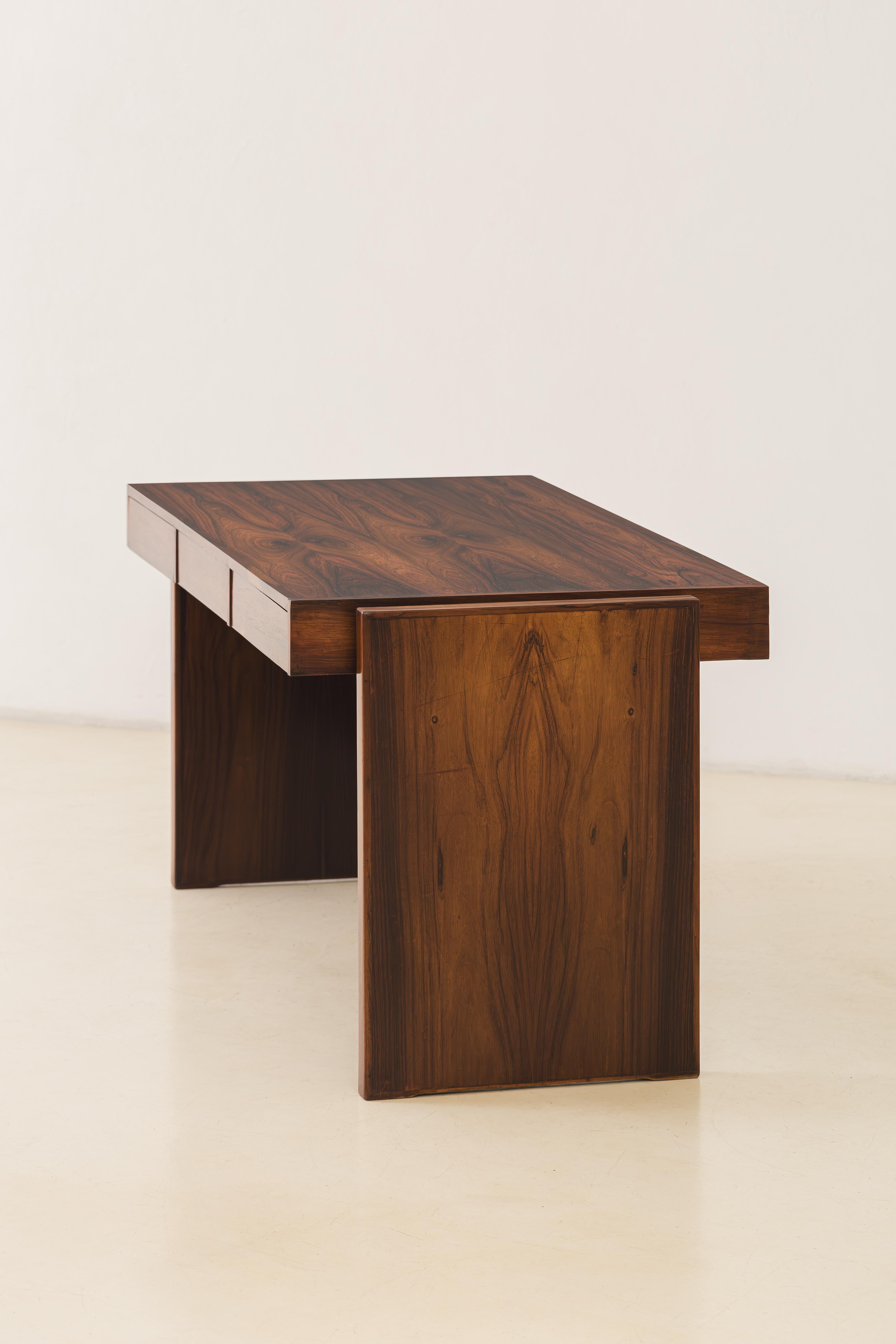 This bloch desk was designed by Joaquim Tenreiro (1906-1992), the “father” of Brazilian modernism, in 1965. The desk offers an interplay of rosewood tones and its elegance is complemented by its functionality, as it has three spacious drawers to