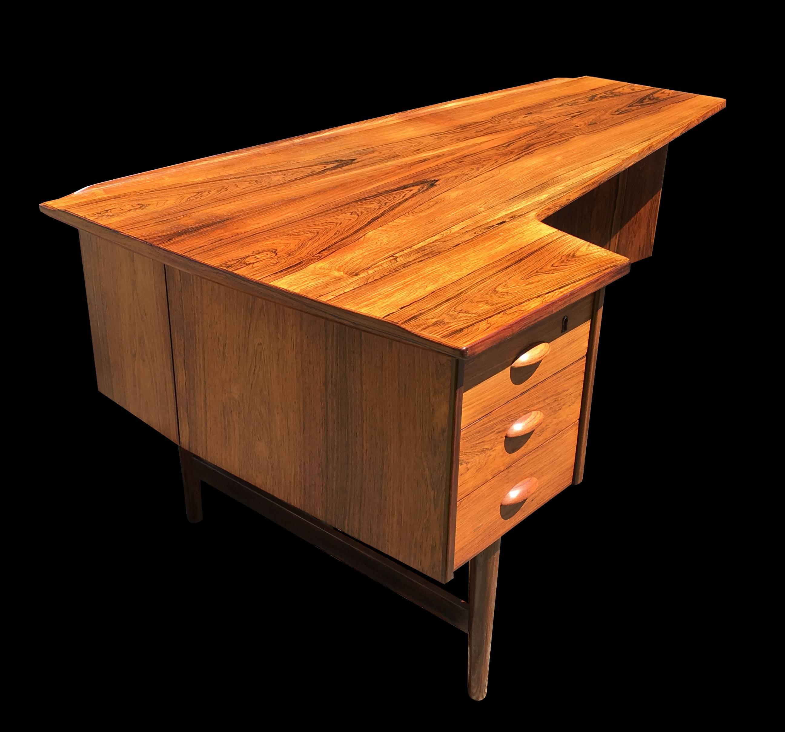 A very good example of this quality desk by Peter Lovig Nielsen, made in Denmark by Hedensted Mobelfabrik, three drawers on one side, and an open bookshelf and small mirror backed cocktail cupboard on the reverse. All on four turned legs with
