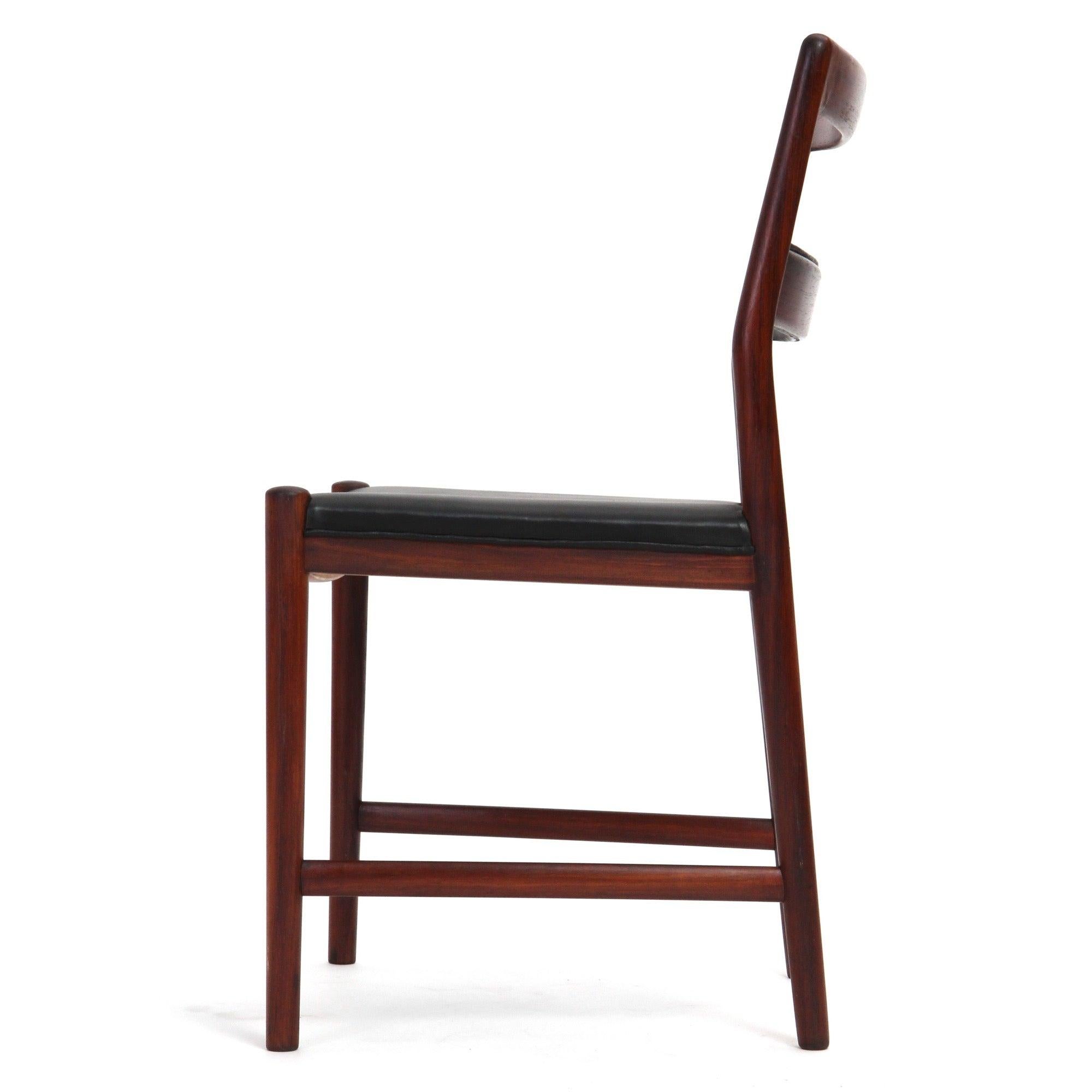 A fine, sculptural and spare group of ladder back dining chairs having luminous Brazilian rosewood frames with black leather seats and expressive leather-wrapped center slats.