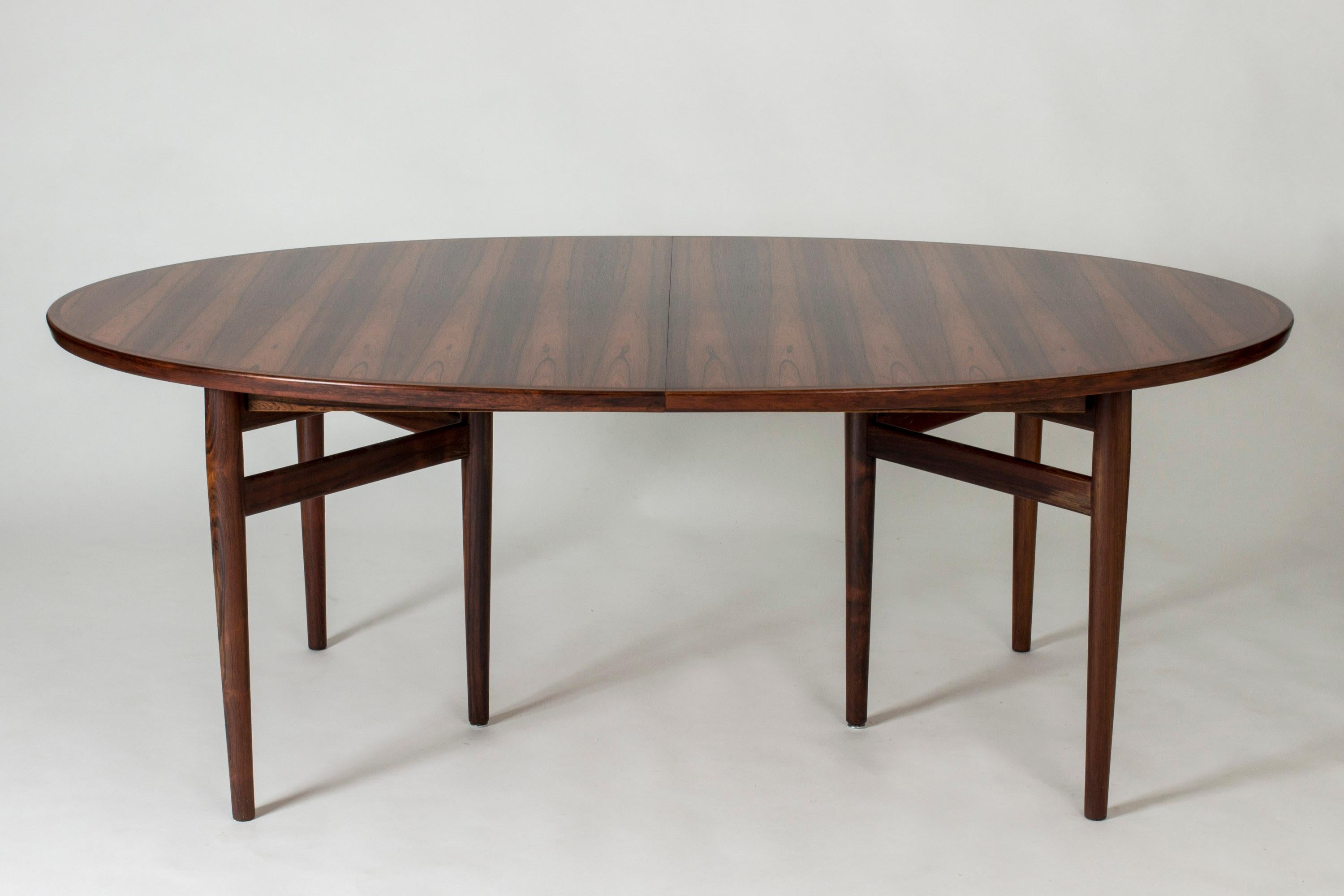 Large, oval dining table by Arne Vodder, made from rosewood. Six legs set in a triangular formation at each end. Two extension leaves that match the nuance of the table very well.

Size: Height 72 cm, width 197.5 + 49.5 + 49.5 cm, depth 123.5 cm.