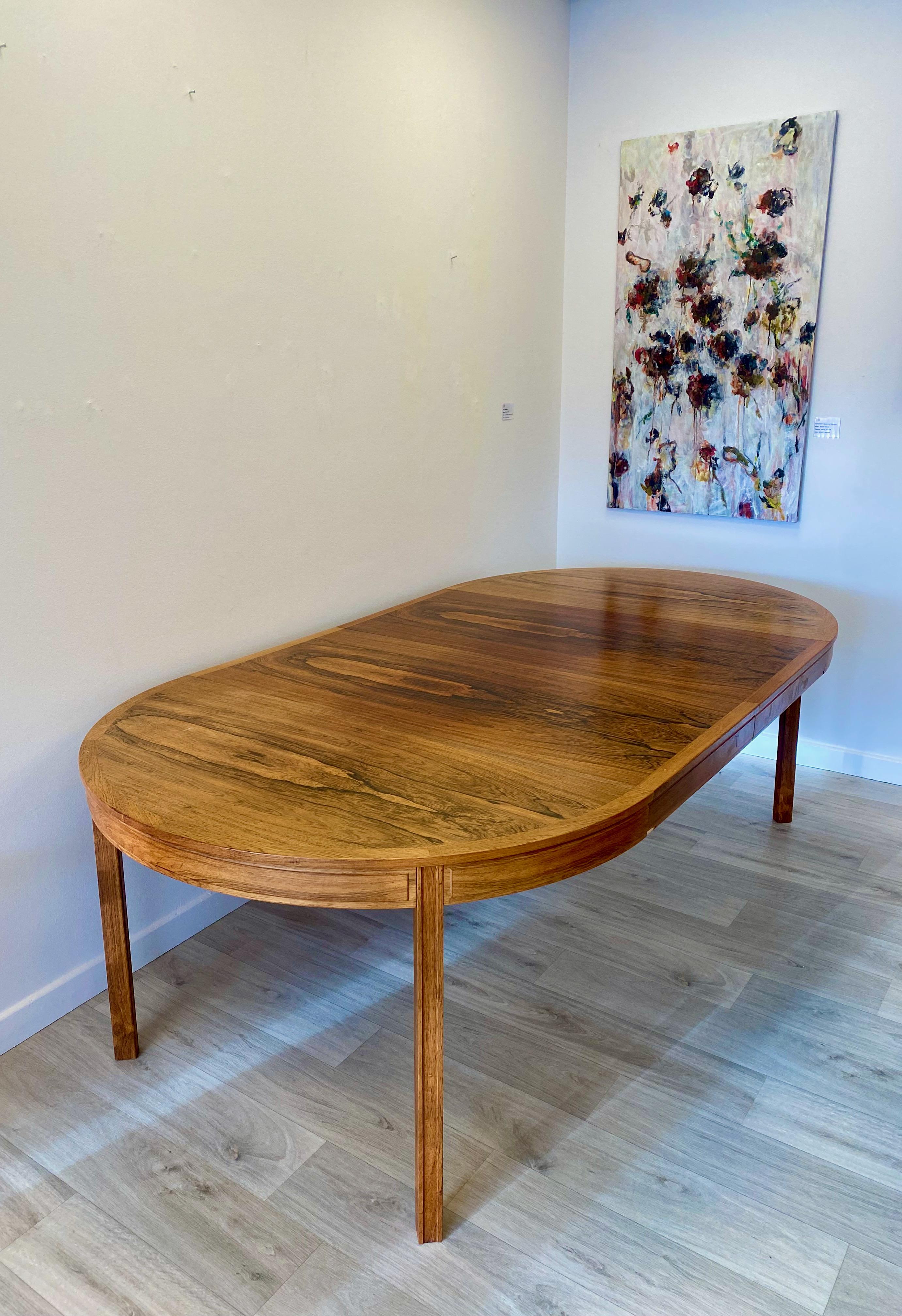Rosewood dining table. Design Bertil Fridhagen for Bodafors. 2 extra leaves. Without the extra leaves it is a round table with a diameter of 120 cm. An exclusive series where the extra leaves have the same low edge as the table. With the extra