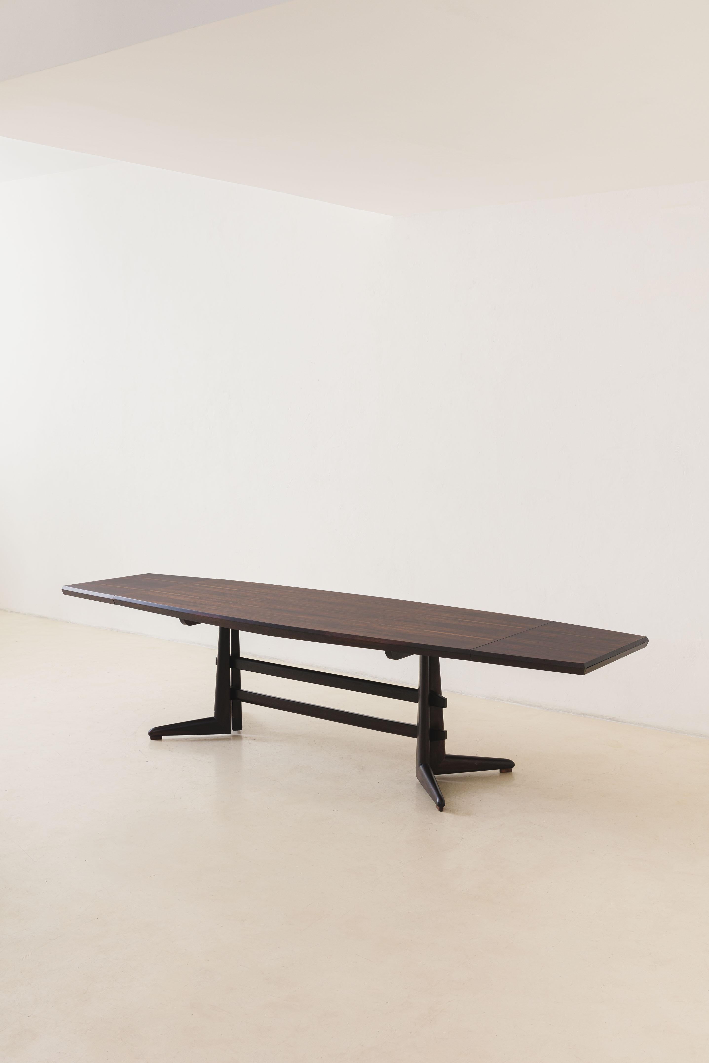This fantastic dining table was designed in the 1960s by Jean Gillon (1919-2007), a Romanian-born architect, artist, and designer who landed in Brazil in 1956. The piece has a solid Rosewood structure, with a veneered top and extensions that