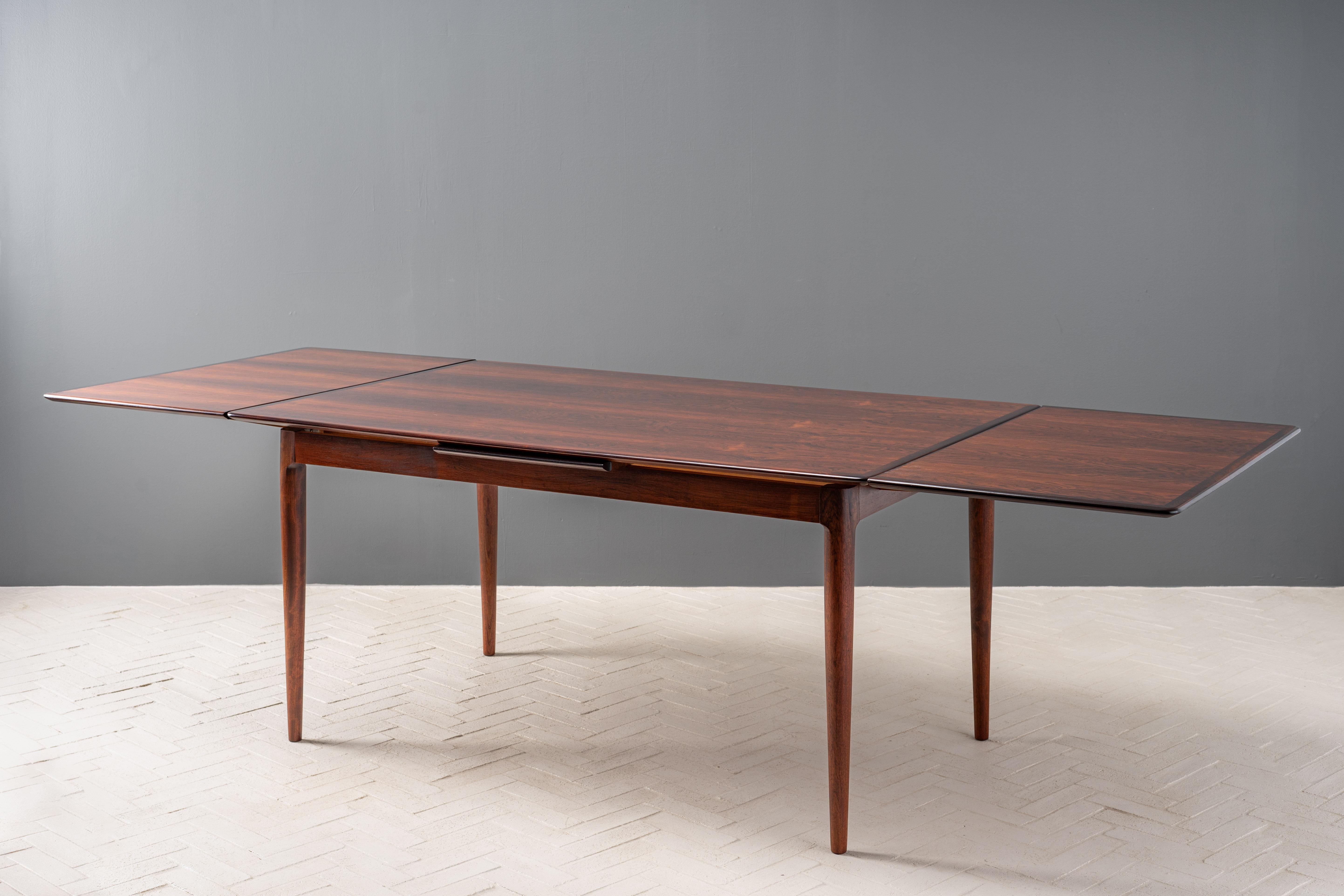 Denmark, ca. 1960s. A stunning rectangular dining table designed by Skovmand and Andersen for Moreddi. Features a beautifully grained top that cleverly conceals two large self-storing leaves - easily lifting from either side to create a generous