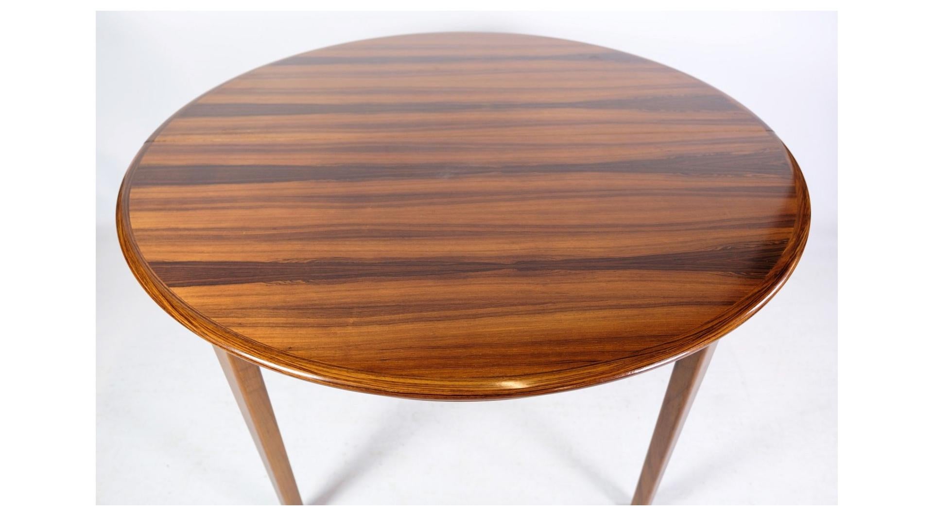 The rosewood dining table, designed by Johannes Andersen and manufactured at Uldum Møbelfabrik in the 1960s, is a remarkable example of mid-century Danish furniture design. Renowned for its exquisite craftsmanship and timeless elegance, this table