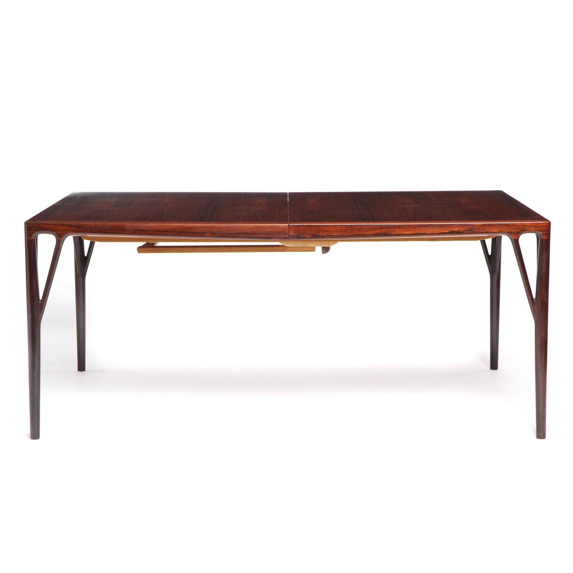 Table de salle à manger à rallonge en palissandre massif, extrêmement rare et de qualité ébénisterie, avec trois rallonges. Chaque feuille est munie d'un tablier assorti à celui de la table, ce qui lui confère un aspect homogène lorsqu'elle est