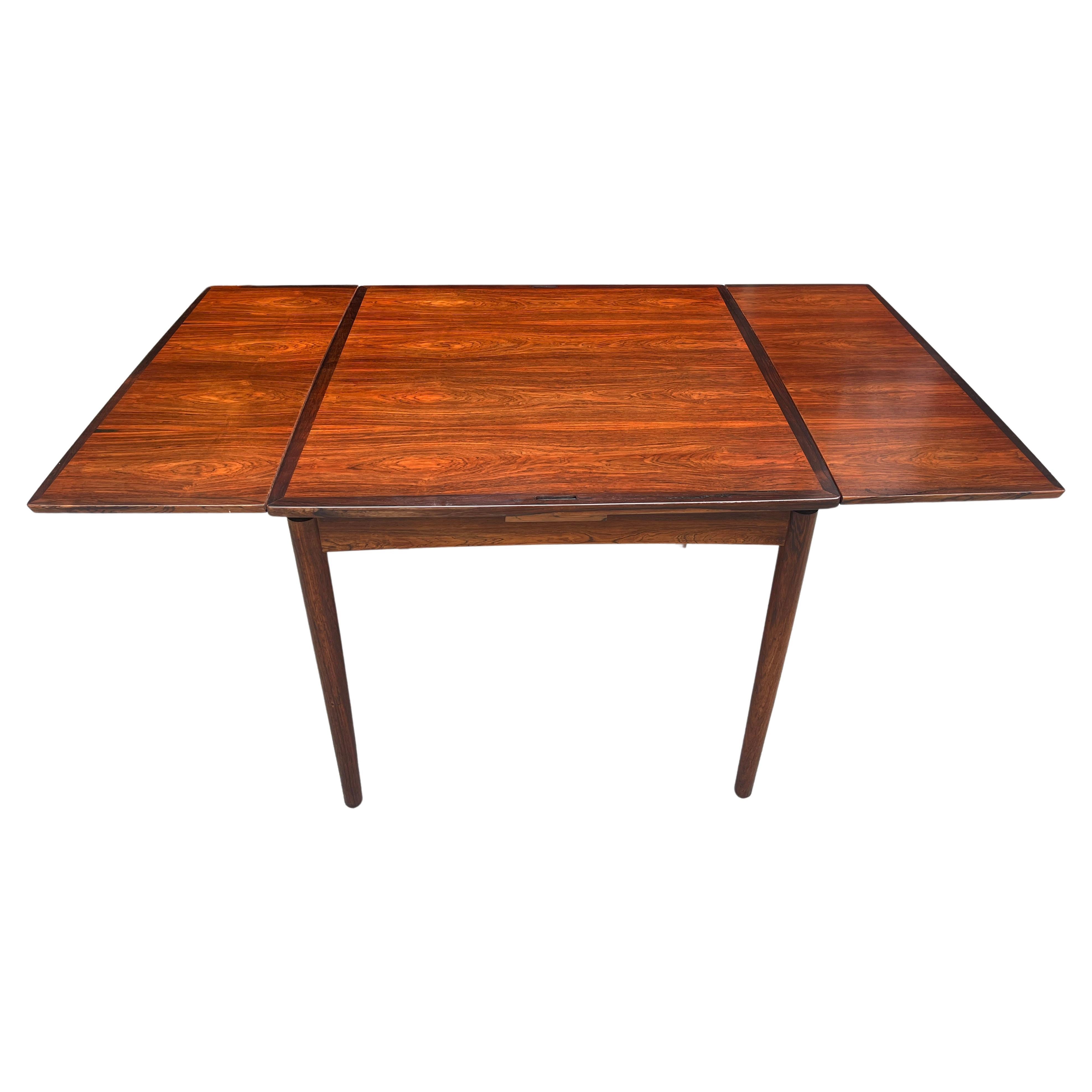 Rosewood dining table designed by Carlo Jensen for Hundevad & Co. This practical design is perfect for smaller spaces. The table can be used with the rosewood top and the leaves tucked in or extended. The square top can also be flipped over to use