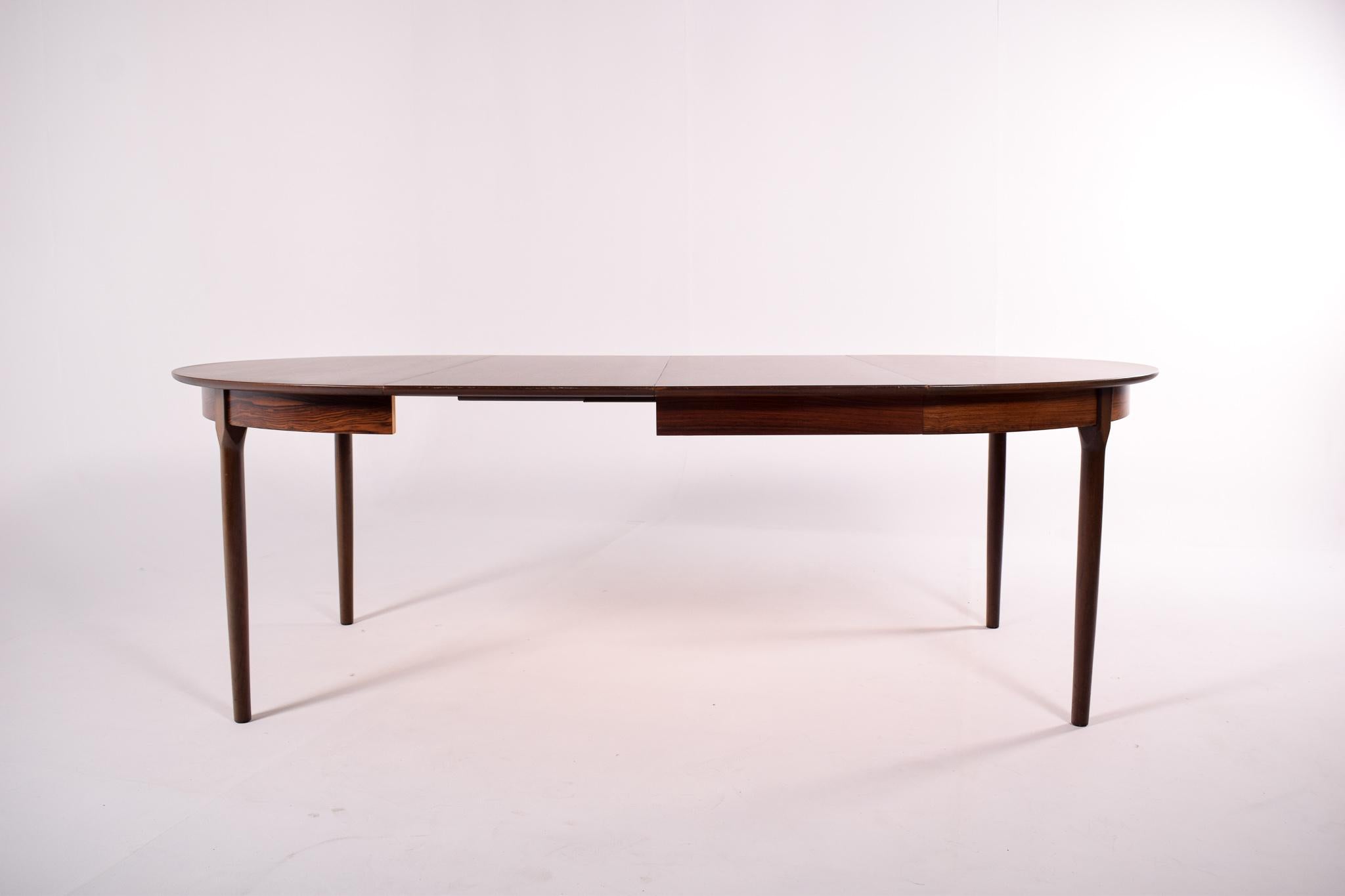 This round dining table, with its beautiful rosewood grain, is exemplary of midcentury Danish workmanship. Expanding to oval with one or two leaves. Each leaf has 49 cm.