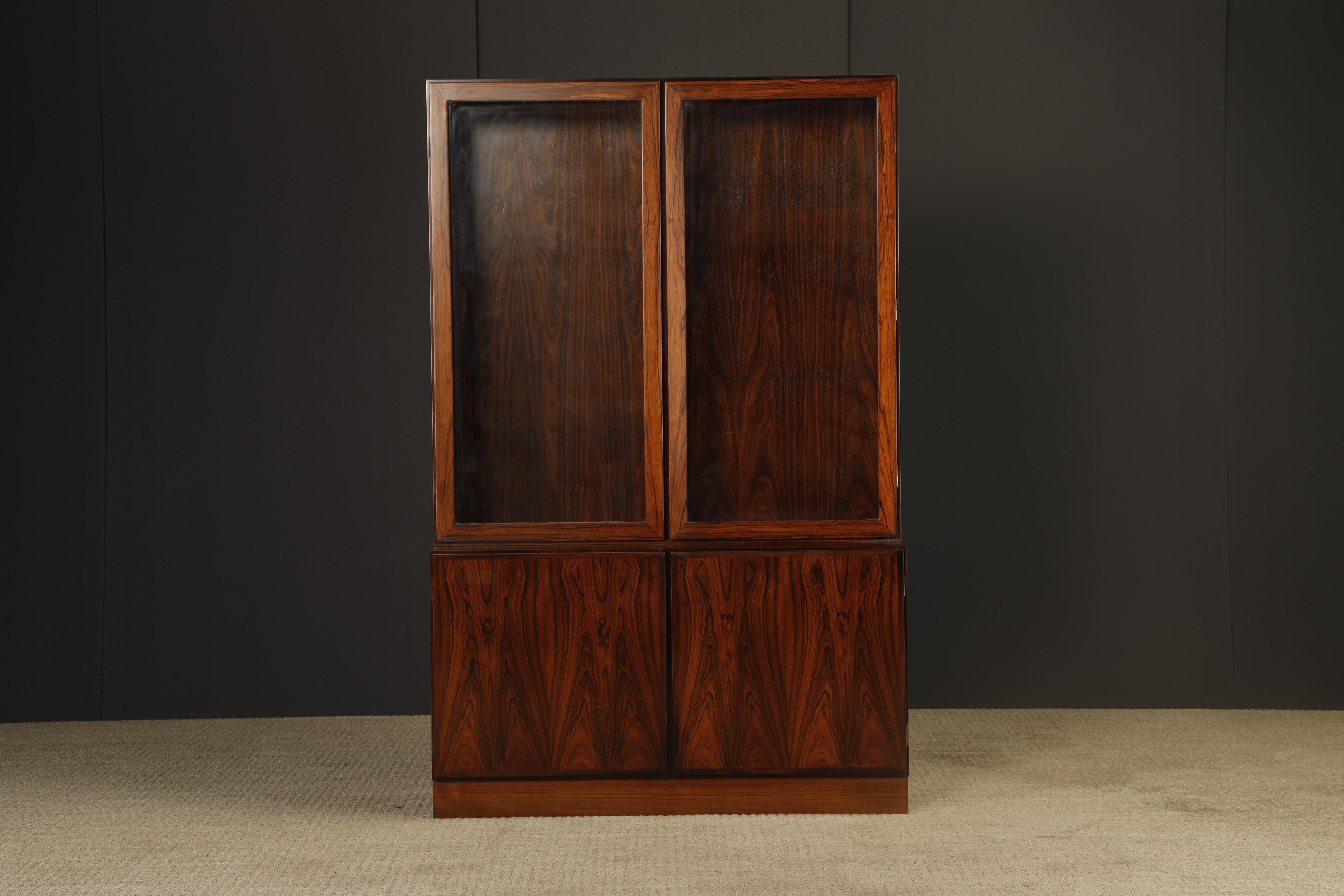 A fine Danish Modern two-piece rosewood display cabinet, Model No. 10, designed and produced by Gunni Omann for Omann Jun Møbelfabrik, Denmark, circa 1960s, double signed, on both the upper and lower portions. 

This elegant two-part cabinet with