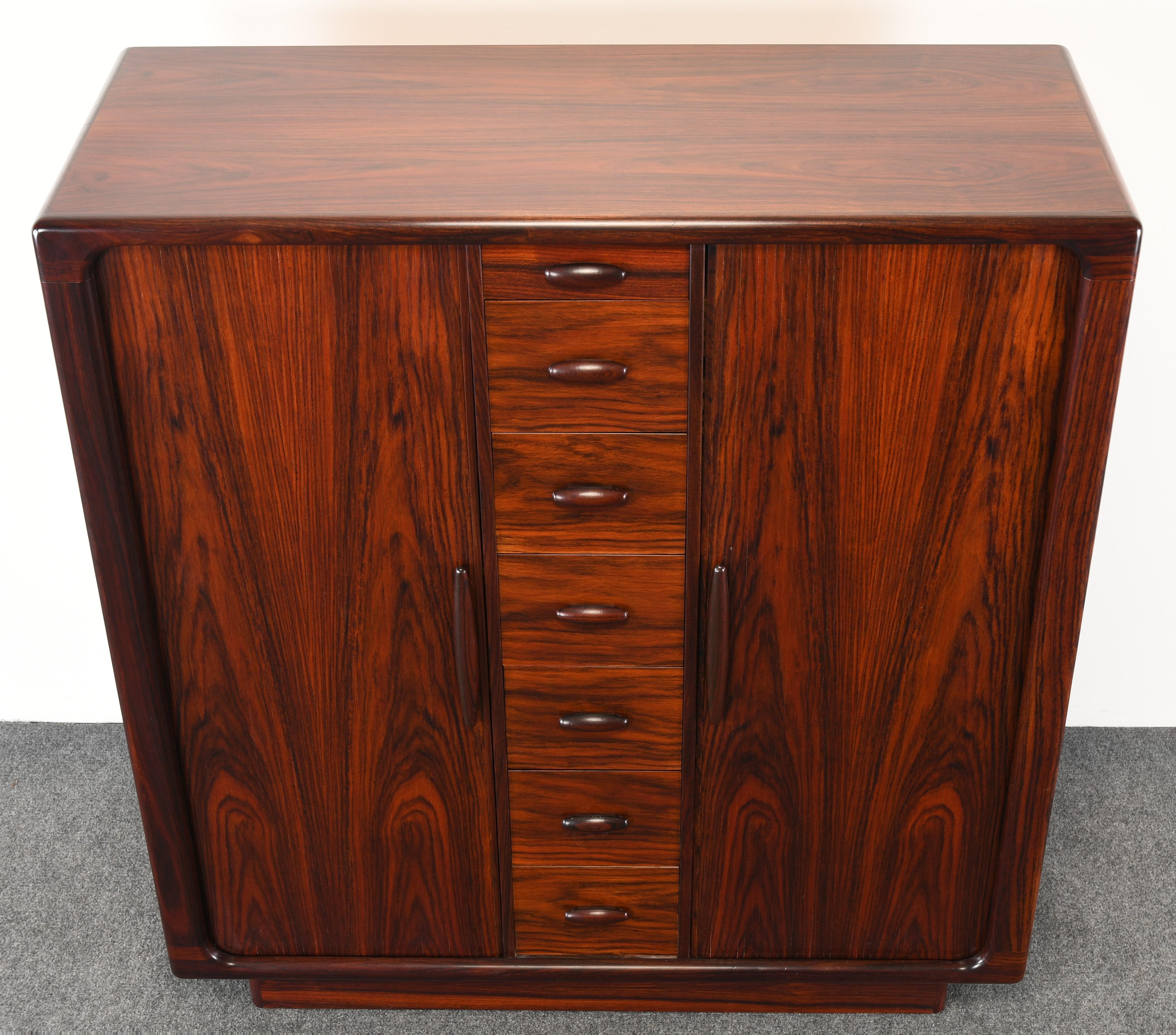 A gorgeous Danish rosewood dresser or cabinet by Dyrlund. This chest of drawers would look great in any contemporary or Mid Century Modern decor. The dresser has two tambour doors that slide beautifully and open up to reveal 14 drawers and 6 shelves