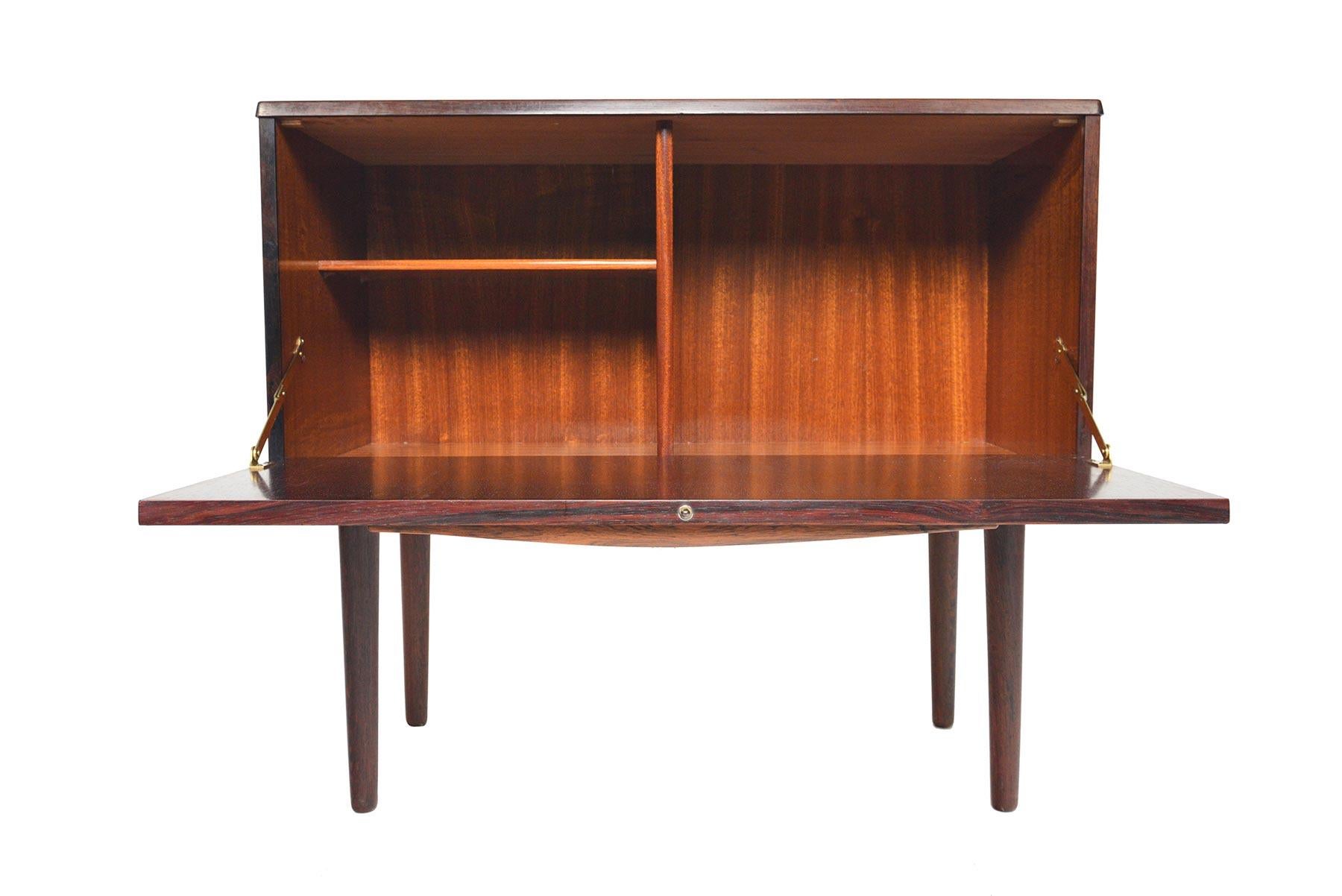 This Danish modern Brazilian rosewood cupboard by Lyby Møbler is an excellent storage piece for the modern home. The door drops to reveal two bays with open storage and an adjustable shelf. In excellent original condition with typical wear for its