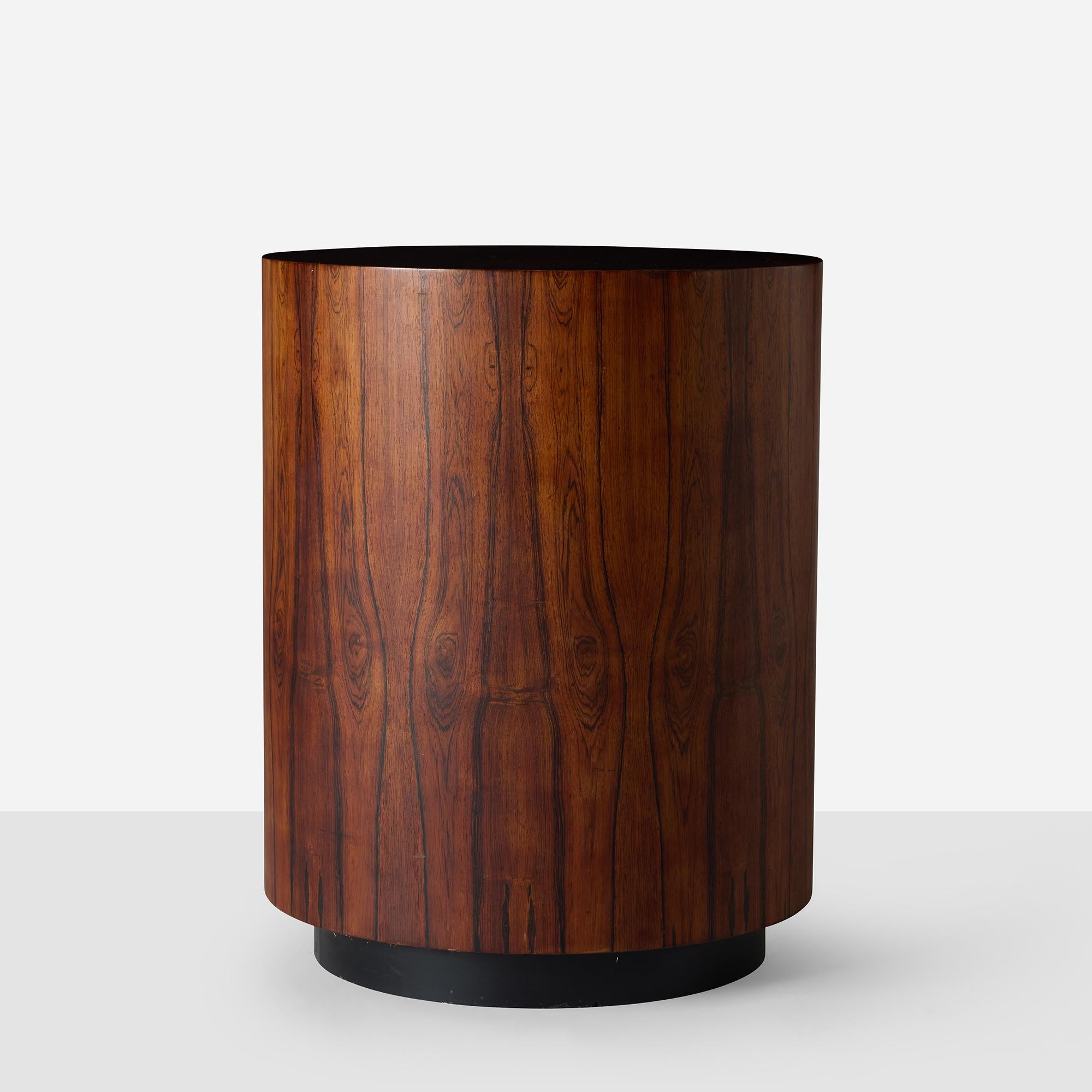 A round occasional table with starburst rosewood veneer top on cylindrical pedestal with castered base. Good condition with light scuffs and wear consistent with age and use, no major scratches or loss to the veneer.
