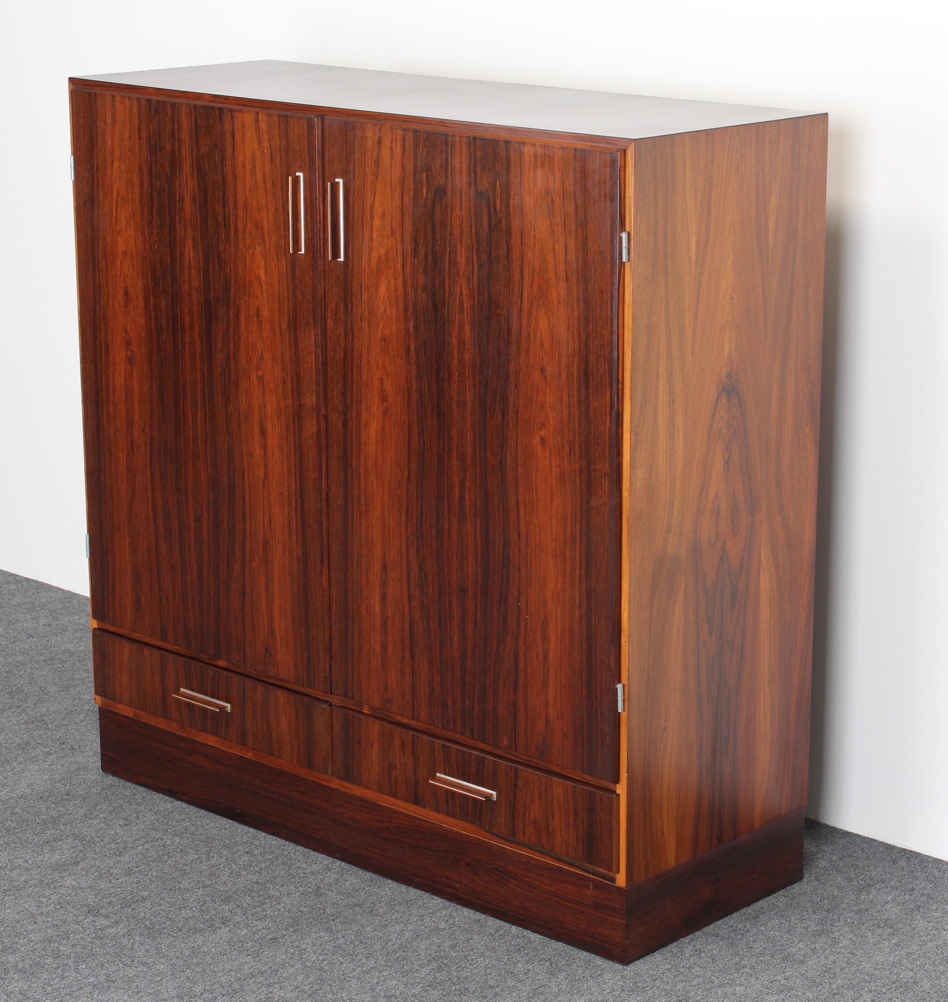 A stunning Danish modern midcentury dry bar in rosewood. Designed by Axel Christiansen for ACO Mobler. Bar has aluminum handles, built in shelf for bottles, a pull-out shelf, adjustable shelf and two drawers for plenty of storage. Interior bar