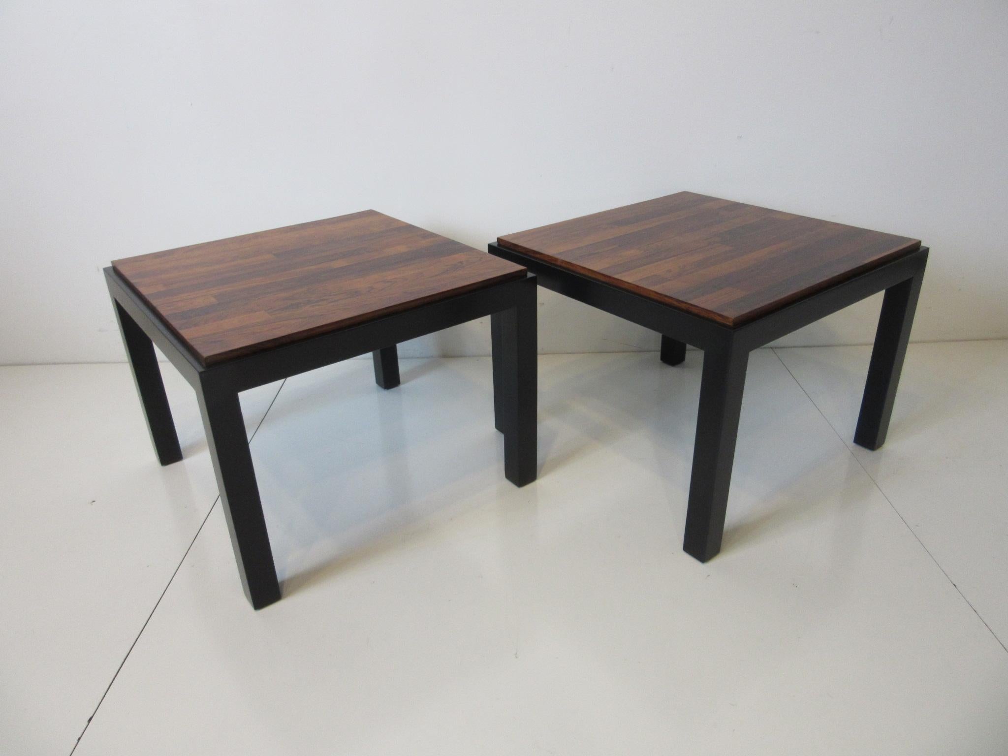 A pair of parson styled side tables with the bases in a dark ebony finish having drop in rosewood tops in the manner of Milo Baughman and the Thayer Coggin furniture company.