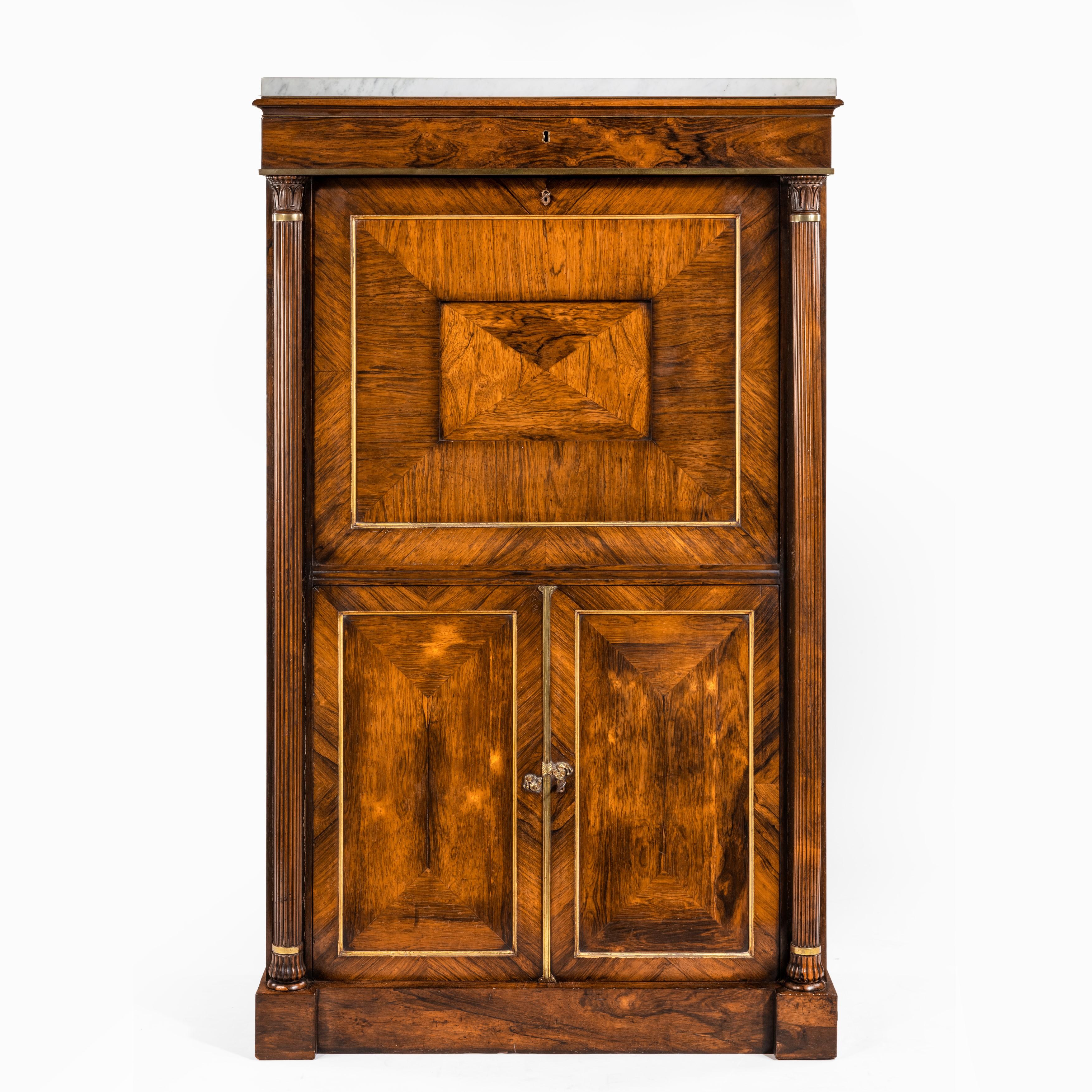 With a white marble-top above a frieze drawer and reeded columns flanking a paneled fall front which opens to reveal three lines of small drawers with pigeon holes above, the lower section with two paneled doors opening to reveal shelves, all on