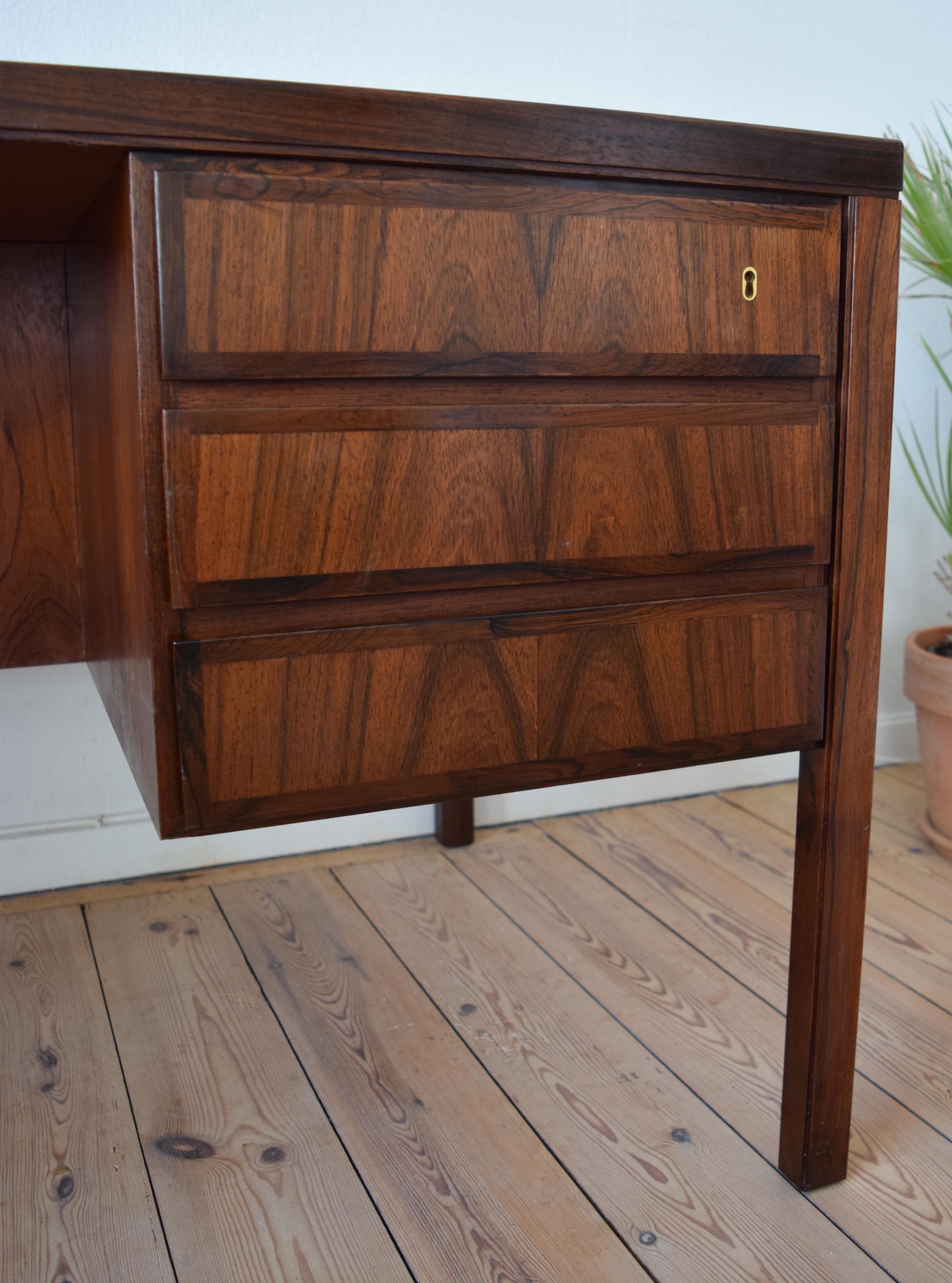 Large executive model 77 desk designed by Gunni Omann for Omann Jun Møbelfabrik, Denmark in the 1960s. This solid desk features six drawers (lockable) with bevelled edges and solid rosewood fronts with matched grain. On the rear are two compartments