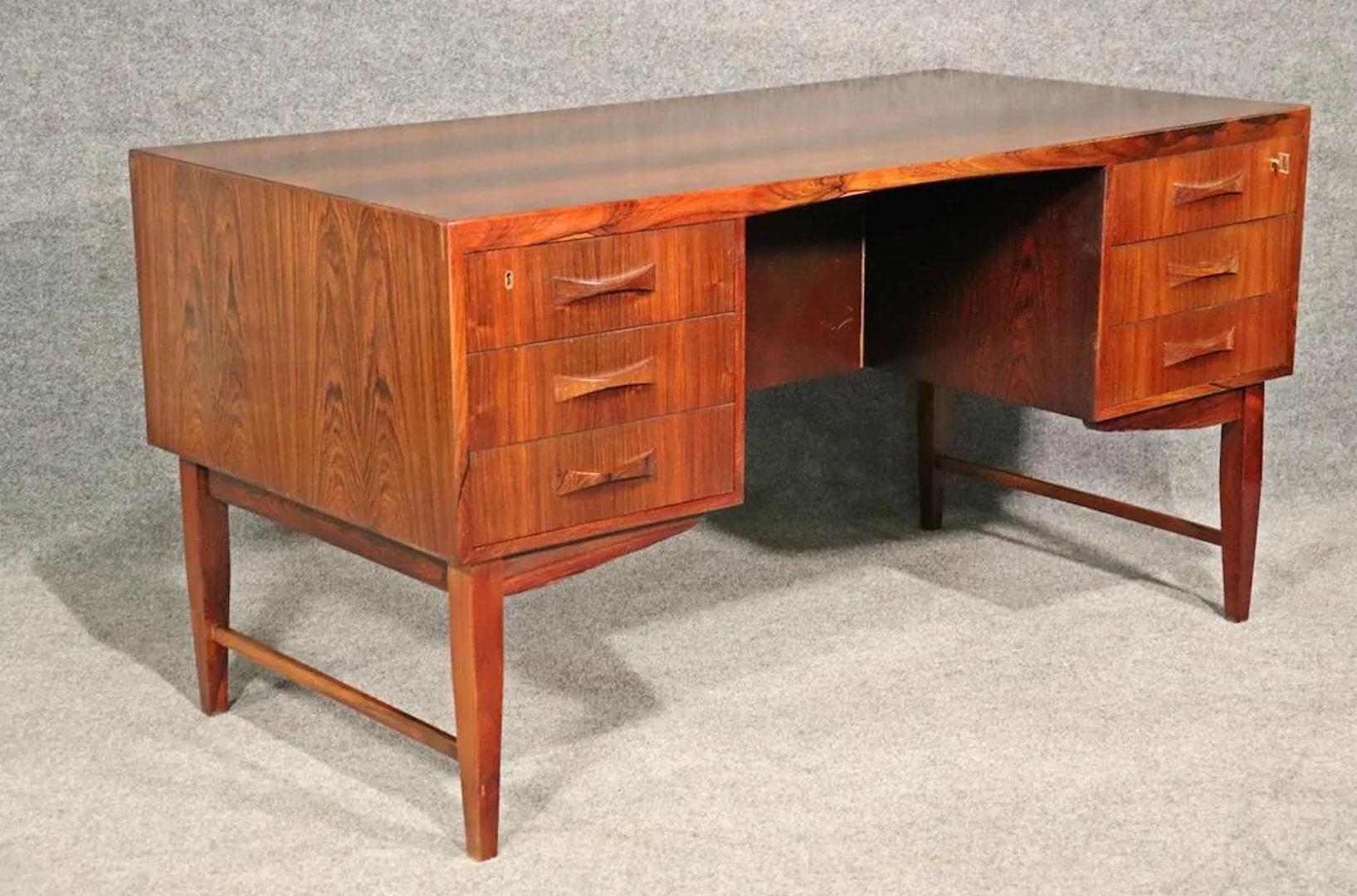 Mid-Century Modern desk in rosewood with finished back. Beautiful office desk featuring bowtie handles, stunning rosewood grain and finished back with cabinet storage.
Please confirm location.