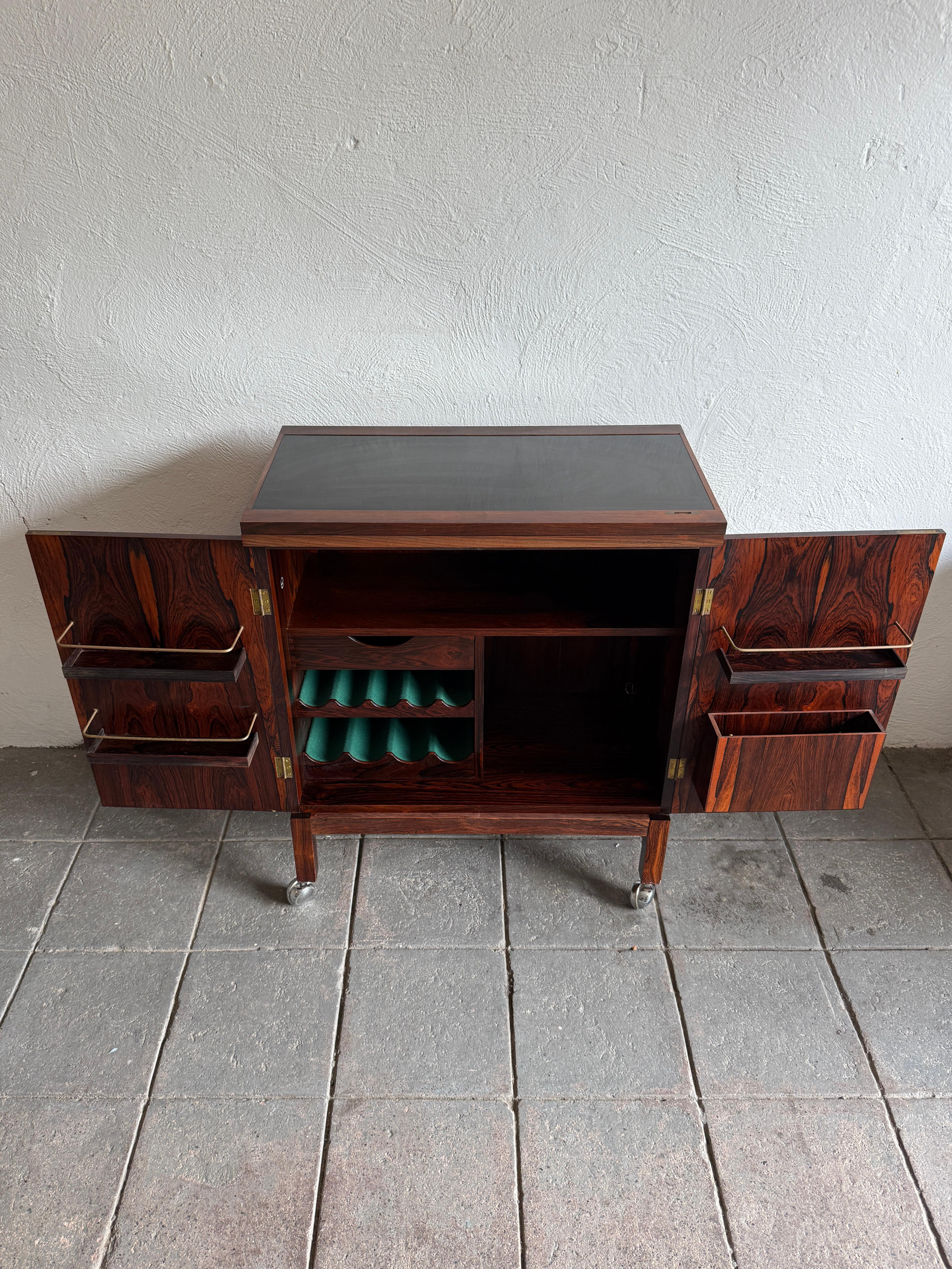 Un impresionante mueble bar vintage de palisandro con tapa abatible, de Torbjørn Afdal para Bruksbo (Noruega). Hermosas vetas de palisandro por dentro y por fuera con intrincados detalles en el interior con detalles de latón. Mucho espacio para