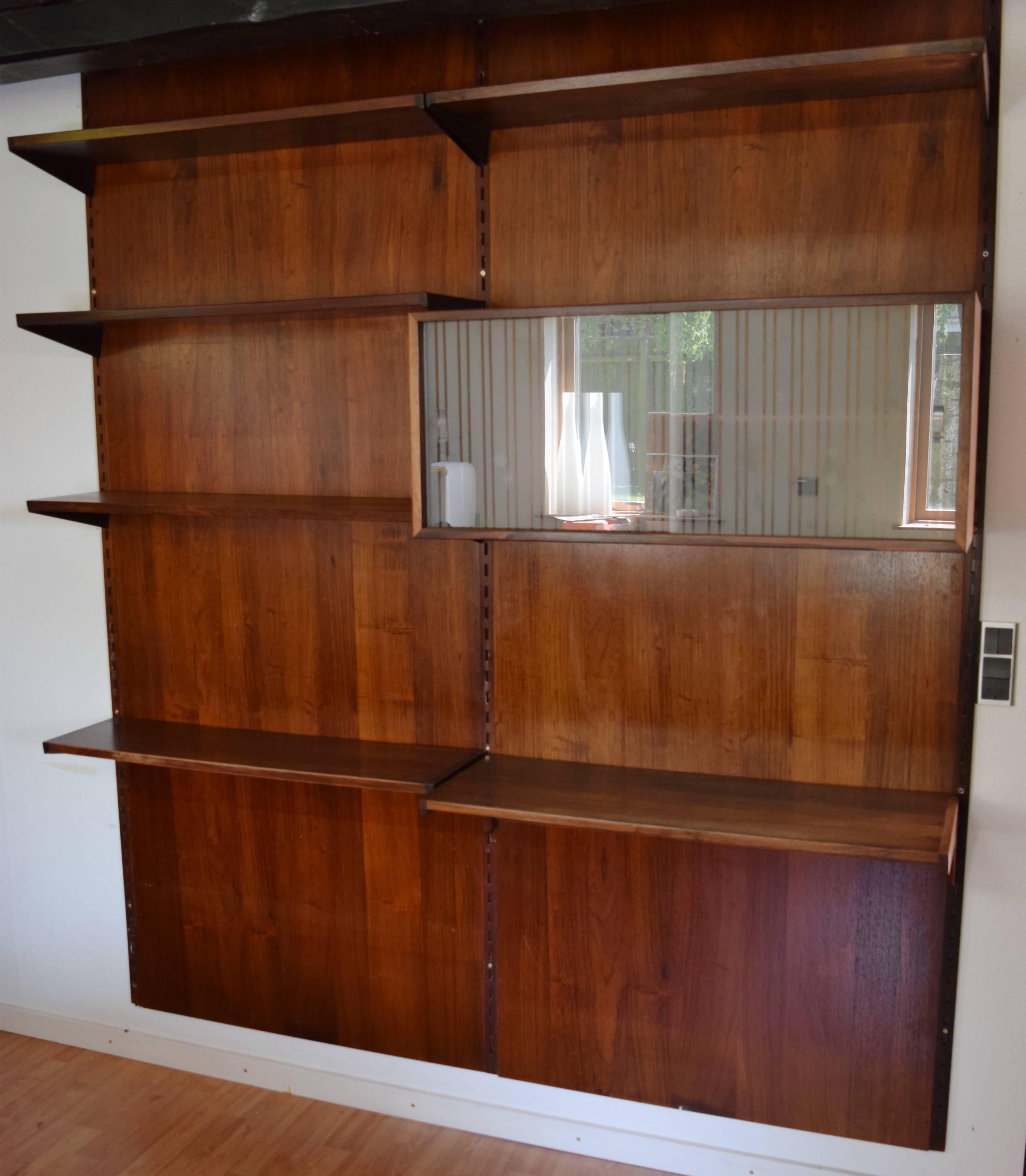 Rosewood wall system designed by Kai Kristiansen and manufactured by FM Møbler, Denmark from the 1960s. This system comprises of six height adjustable small shelves, a cabinet with glass sliding doors and three hanging rails. The rosewood
