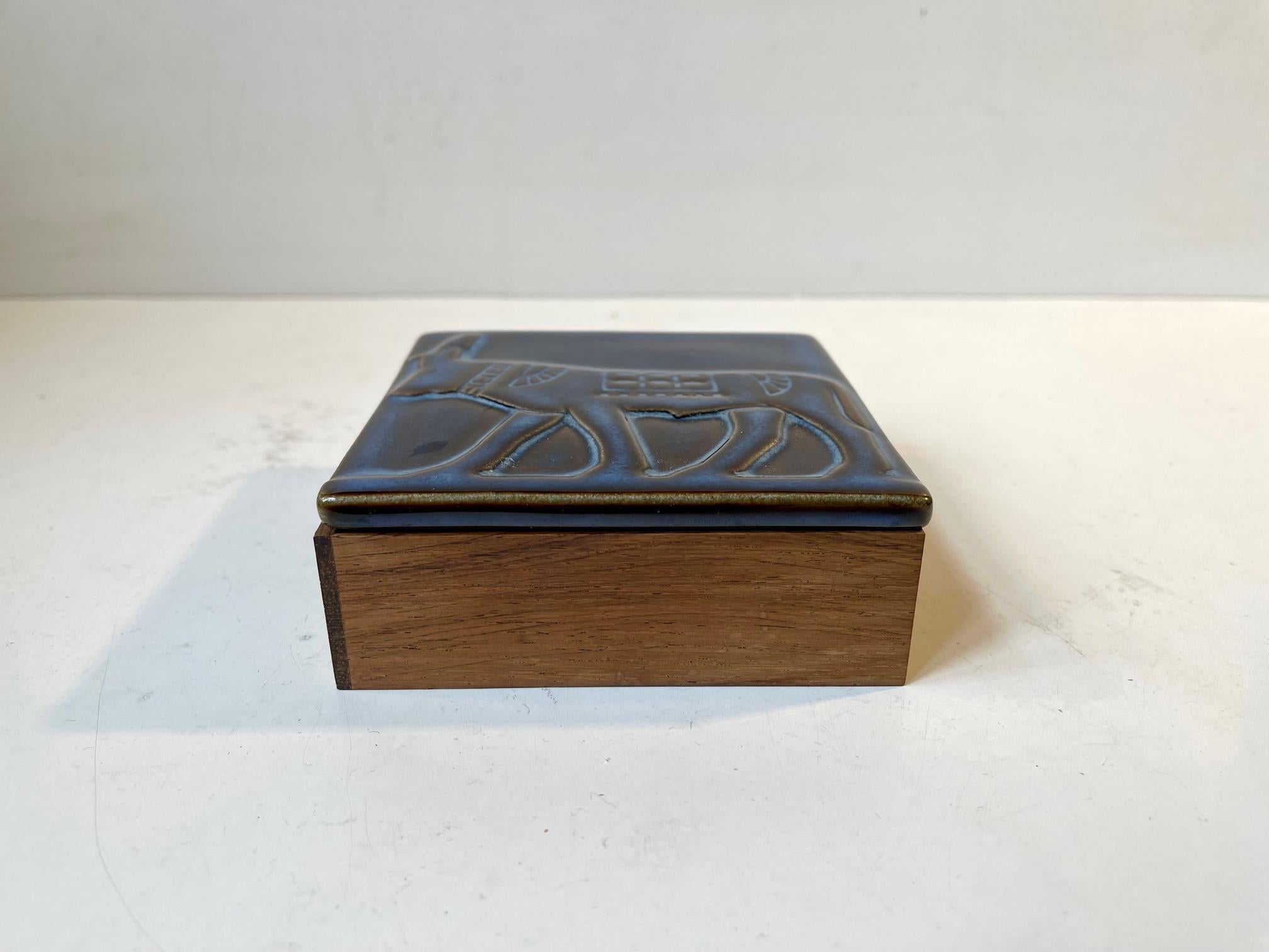 High-quality desk cigarette or decorative box composed of af glazed ceramic lid with a bull in relief, box-sides in solid rosewood upon af plate in black formica. The lid was designed by ceramist Einar Johansen and made at Søholm in Denmark for