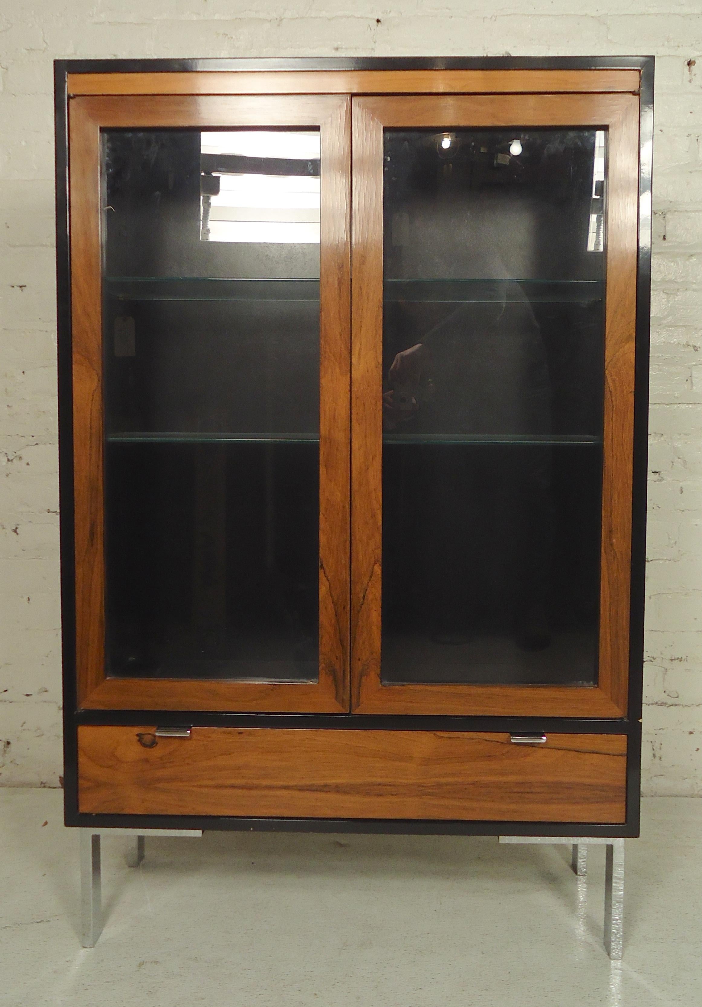 Glass front cabinet with shelves and bottom drawer. Set on polished chrome legs with black trim and sides.

(Please confirm item location - NY or NJ - with dealer).
 