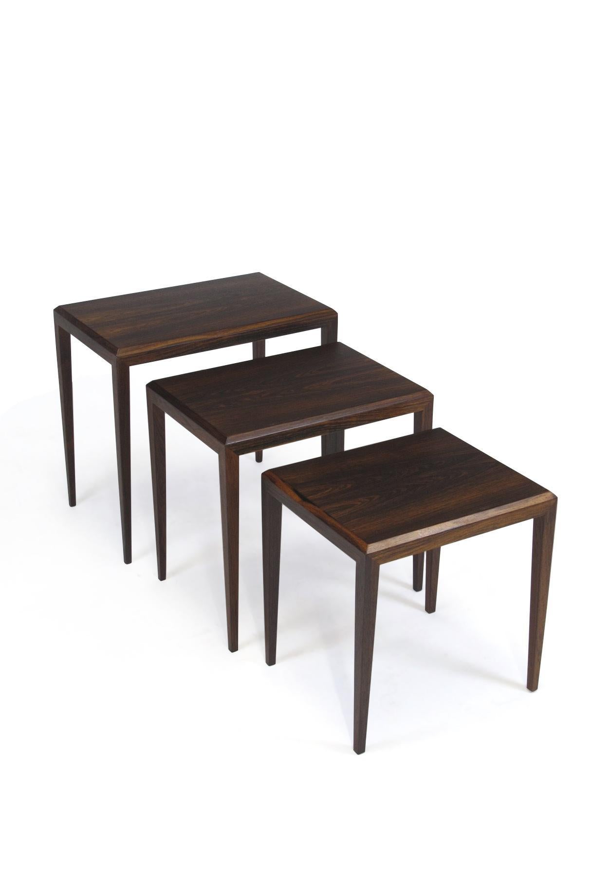 Set of three rosewood nesting tables designed by Johannes Andersen produced by CF Christensen of Silkeborg, Denmark. Nesting system crafted of book-matched rosewood surfaces raised on solid Brazilian rosewood tapered legs. Dark Brazilian rosewood,