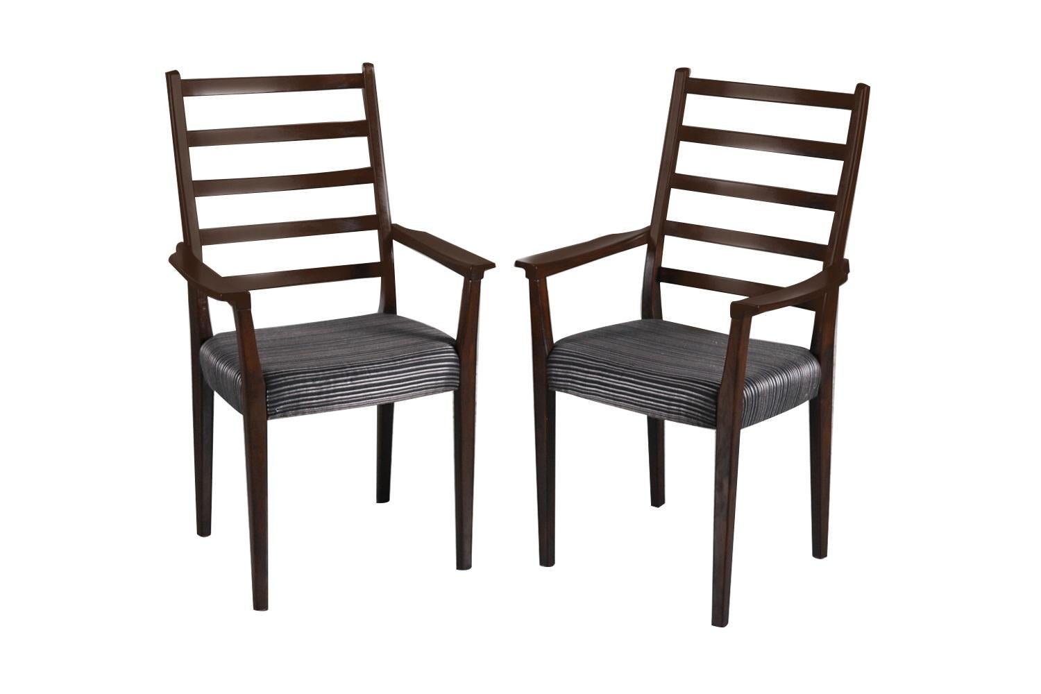 An outstanding set of six Rosewood dining chairs circa 1970's. This stunning set of six ladder back rosewood chairs features two arm chairs and four side chairs in original beautiful black and gray striped upholstered seats. The arm chairs are