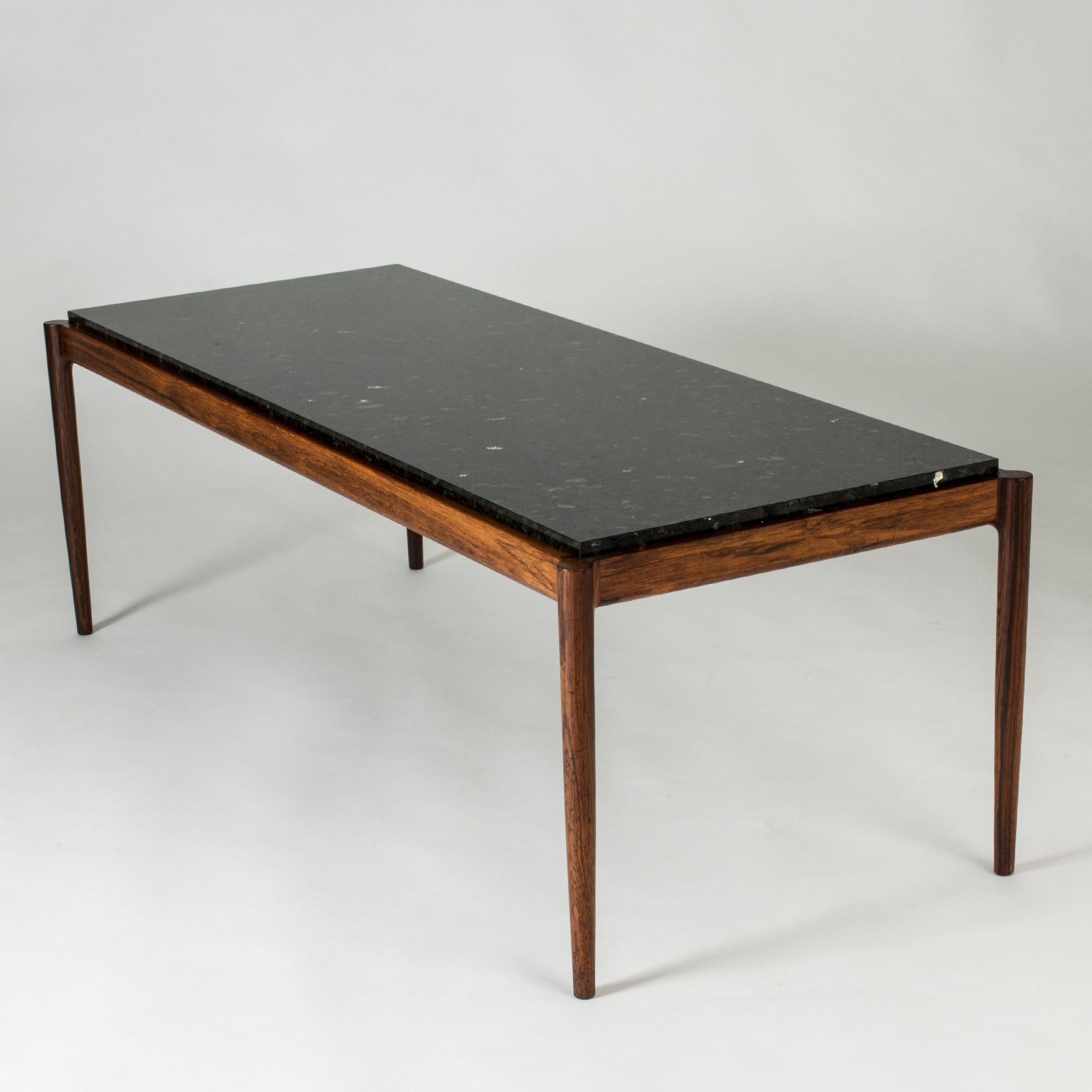 Elegant coffee table by Ib Kofod Larsen, with a rosewood frame and black marble table top. Smoothly rounded corners, subtle glimmer in the table top.