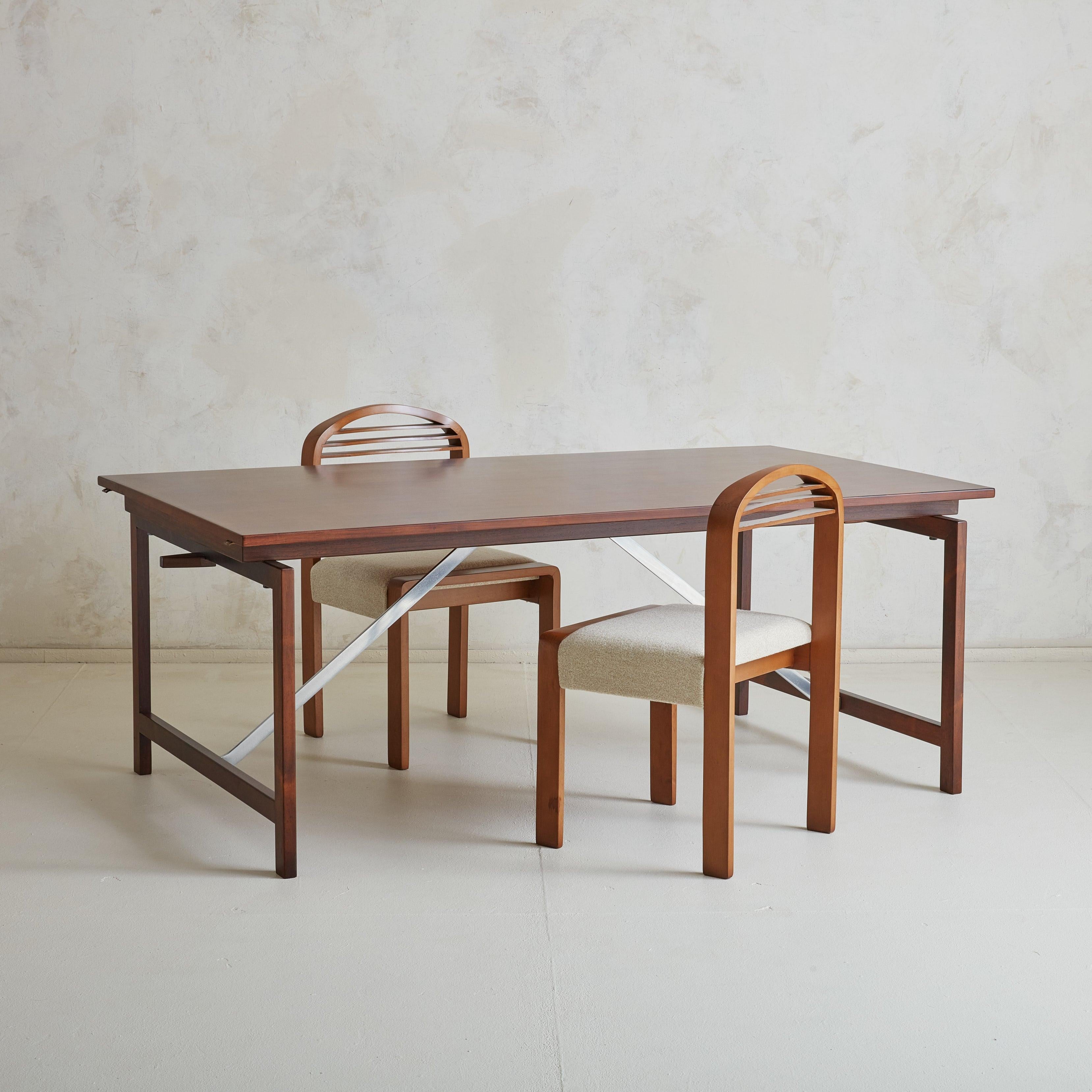 A gorgeous 1960s Danish Modern extendable dining table attributed to Hans Wegner for Johannes Hansen Cabinetmakers. This dining table is composed of beautifully grained solid rosewood in a rich, cherry hue and stands on stretcher accented legs with