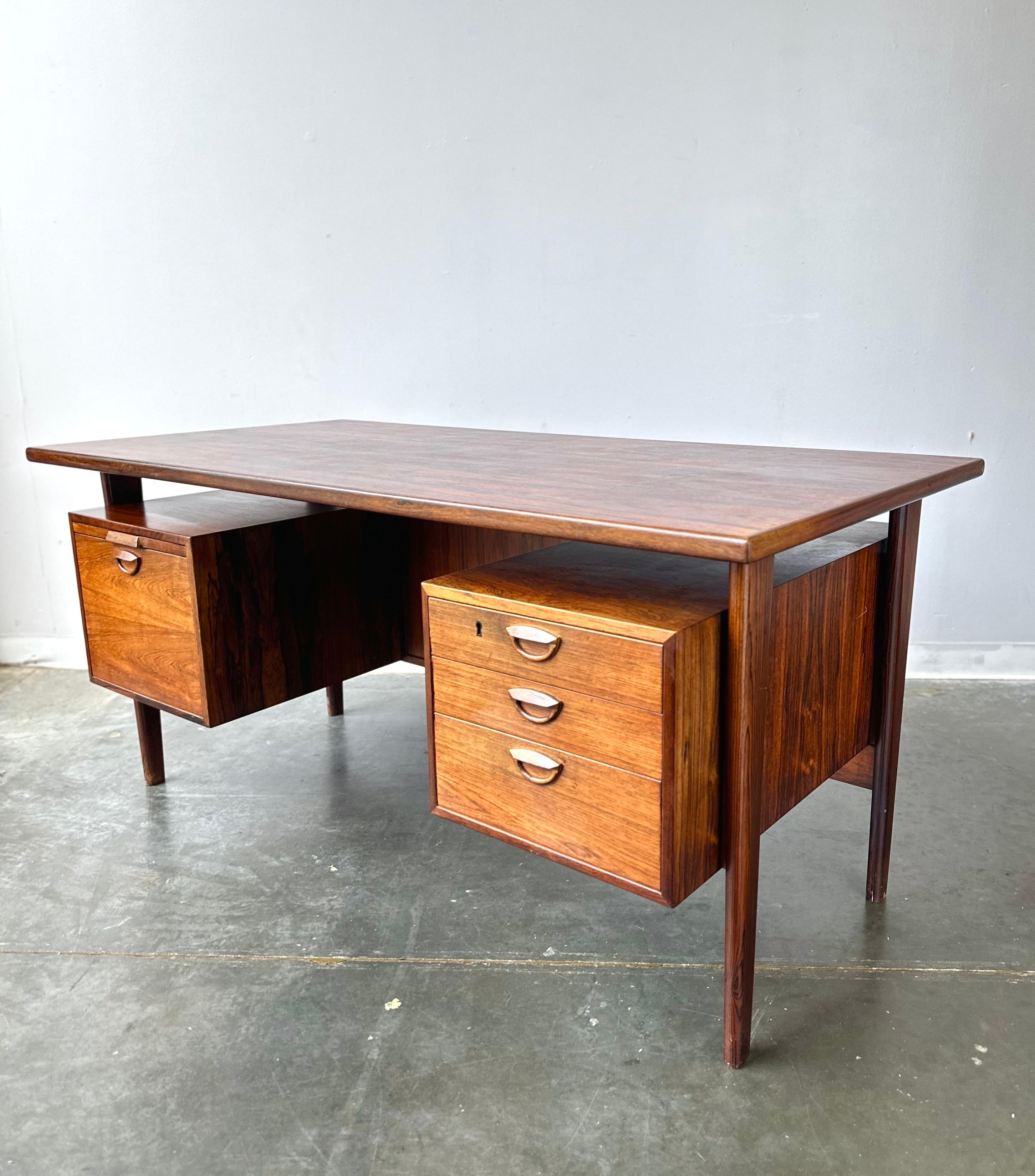 Kai Kristiansen Designed Rosewood Desk 

This stunning piece features excellent rosewood wood grain , a floating design, open bookshelf back, and ample storage space.    It’s in very good condition with minor signs of wear but it presents very well