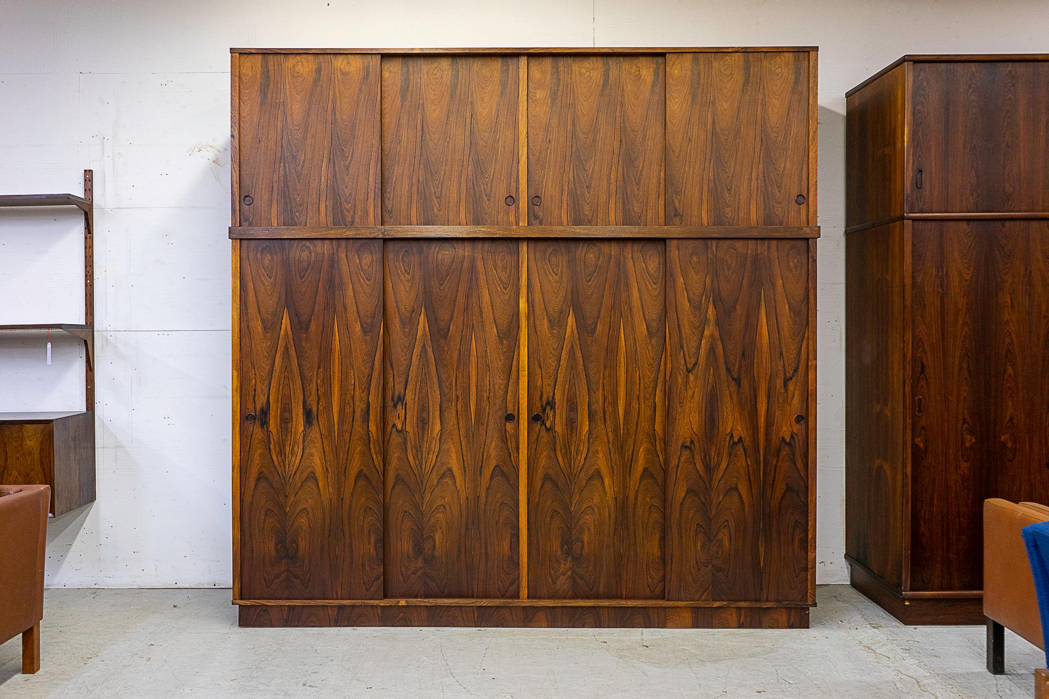 Rosewood quadruple bank Danish wardrobe, circa 1950s. Absolutely stunning grain patterning on this beautifully balanced piece! Highly functional double decker model, with open storage, drawers and hanger bars. Multiple pieces of furniture all