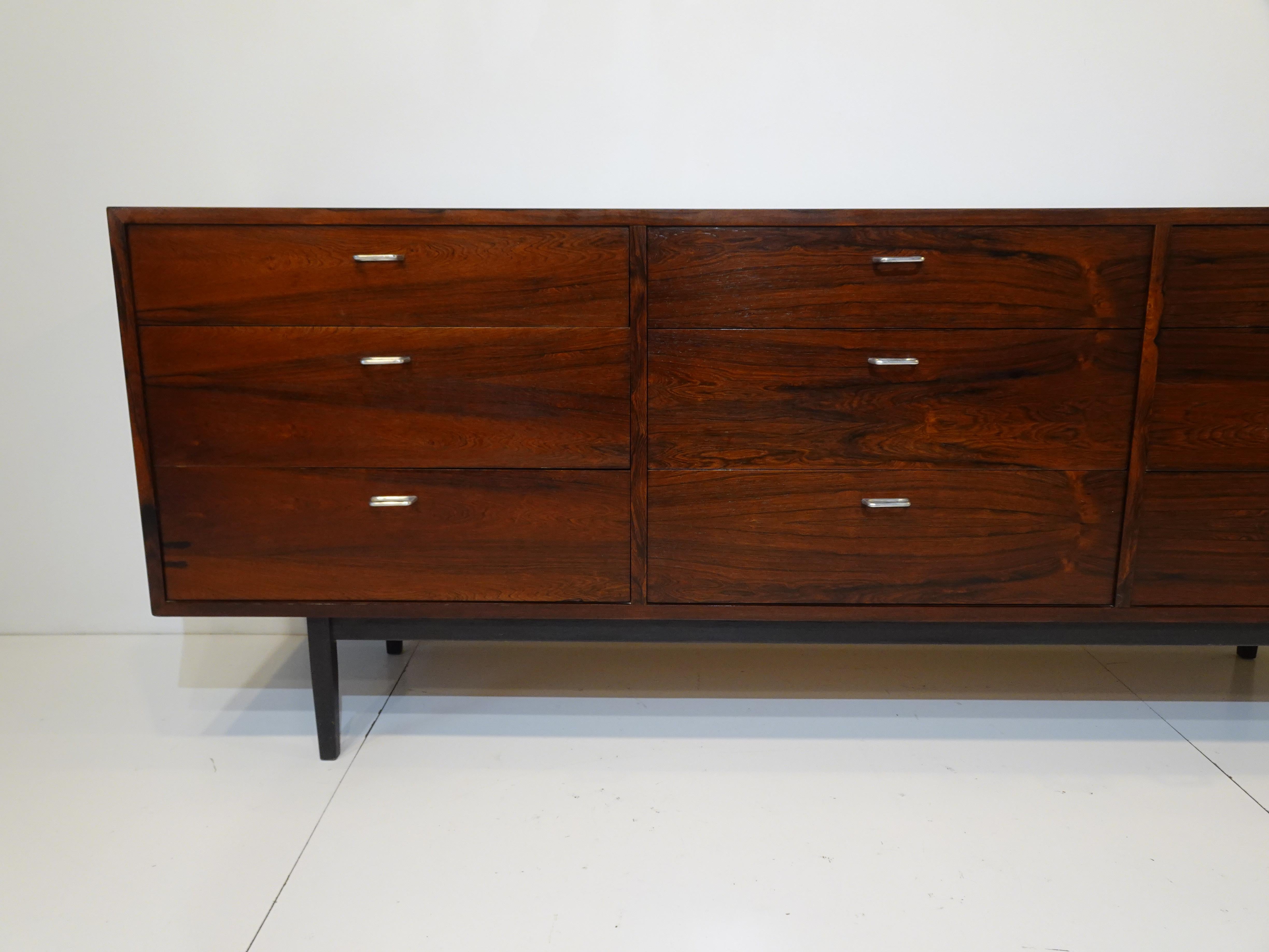 A nine drawer beautifully grained rich and dark Brazilian rosewood dresser sitting on a satin black wood frame and legs. The chest has cast polished metal pulls with oak interiors to the drawers giving the chest a contrasting look with plenty of