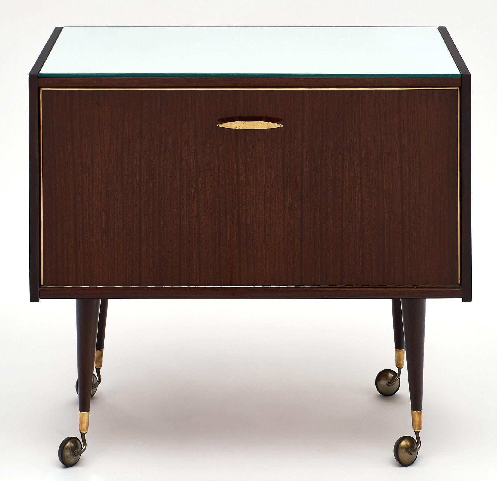 Midcentury vintage rosewood bar cart with mirrored top. This piece features a beautiful rosewood veneer and drop front with brass handle. It opens to a bar compartment including interior shelf for glasses. We love the casters and compact size of