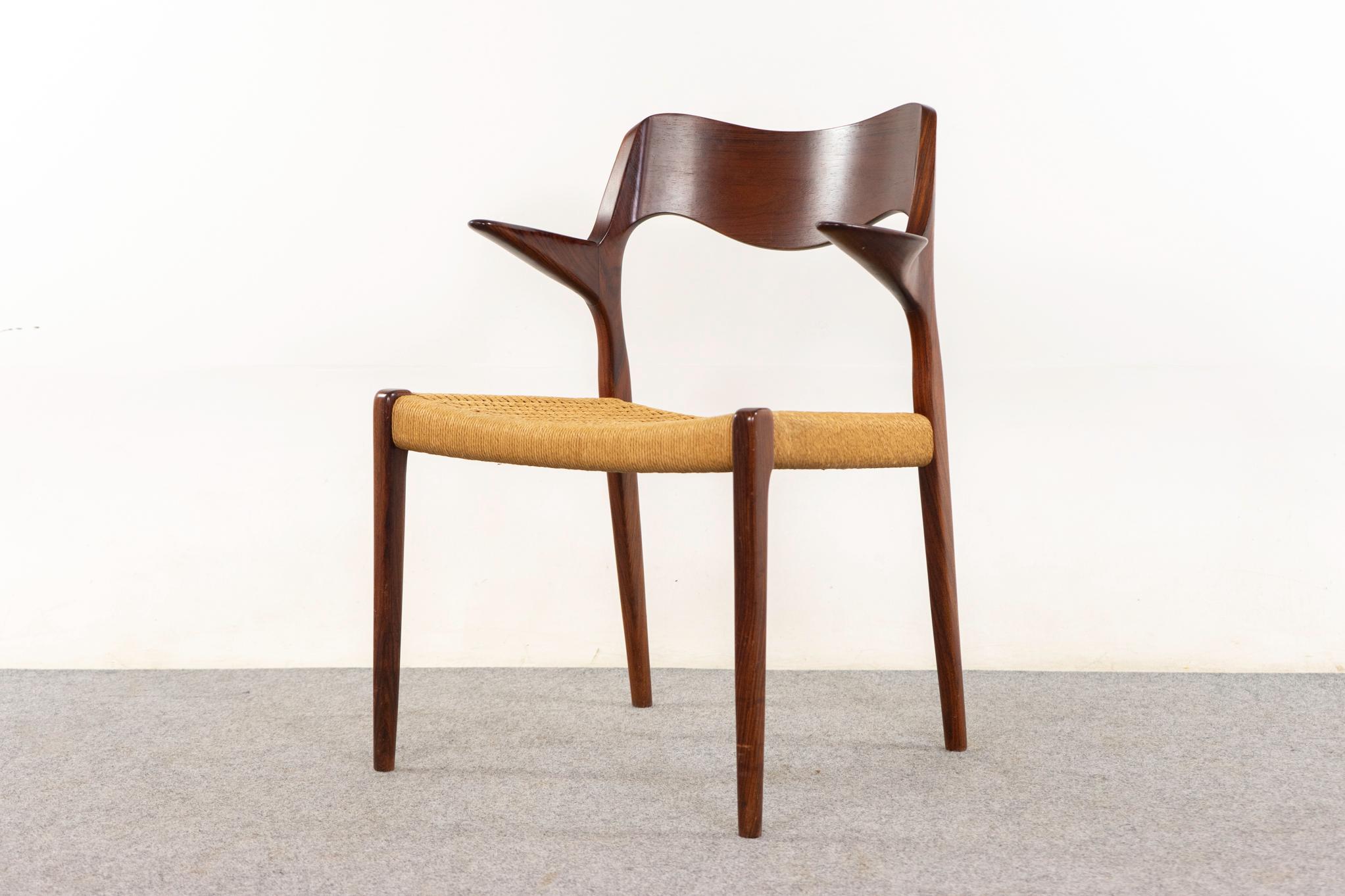 Sillón de palisandro modelo 55 de Niels Otto Moller para J L Moller Mobelfabrik, hacia la década de 1950. Armazón icónico de líneas gráciles y esculturales reposabrazos flotantes. Asiento original de cuerda de papel con desgaste. La marca del