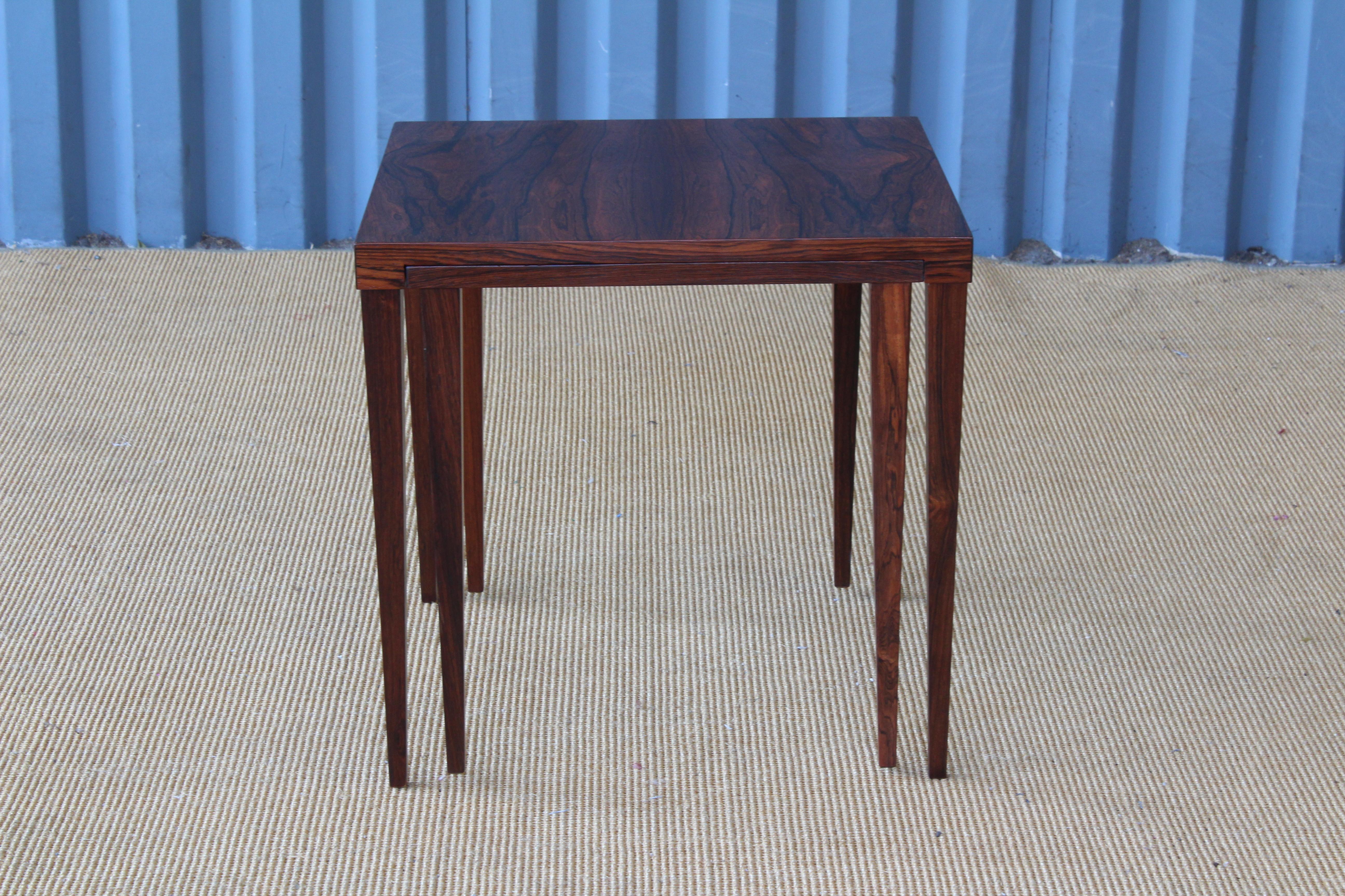 Pair of rosewood tables. Smaller table slides into the larger table. Both have been refinished and are in excellent condition. Marked underneath the smaller table.