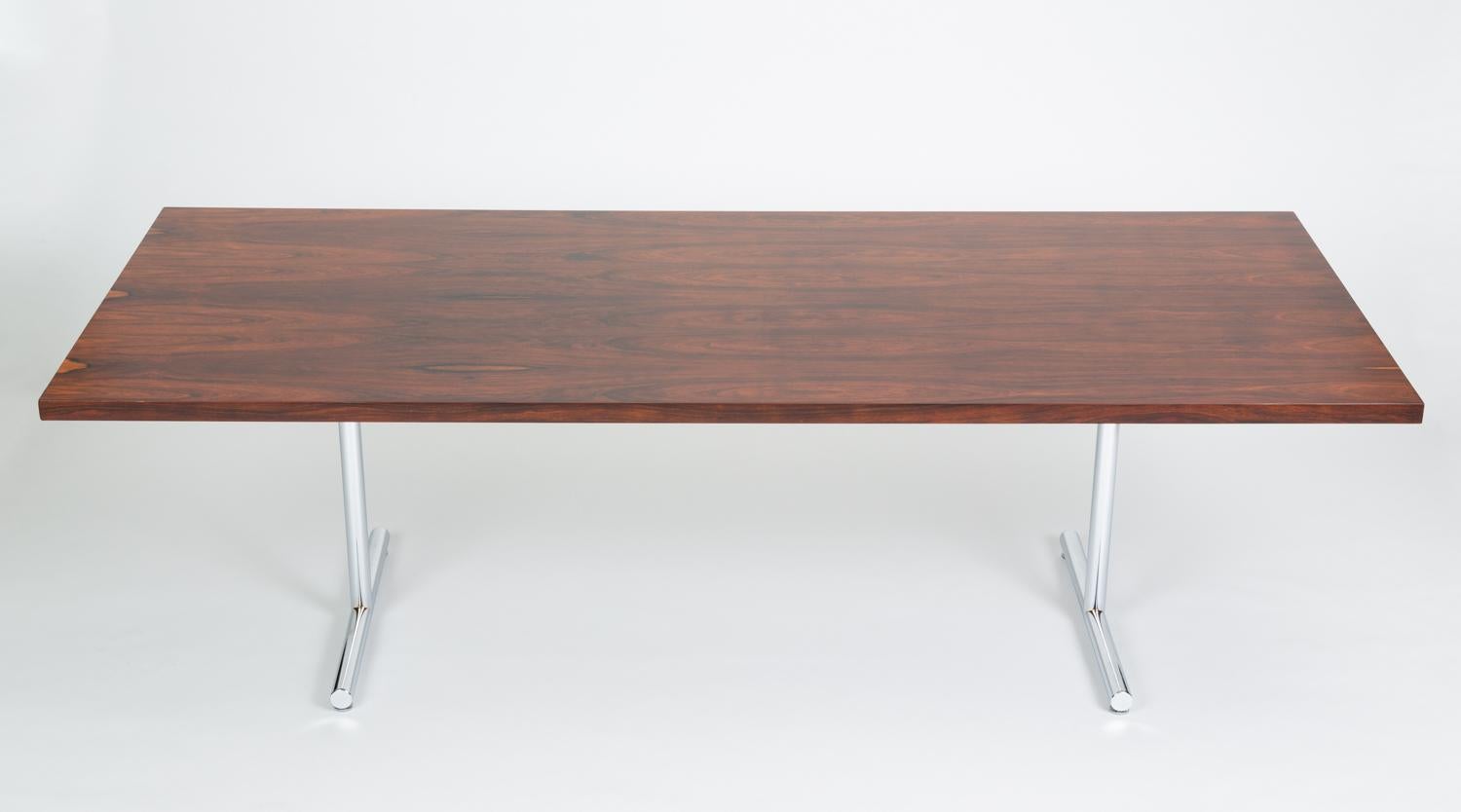 A long rosewood table with a utilitarian minimalism designed by Hans Eichenberger was originally marketed as a “desk-dining table” but could also be used as a conference table. The wooden slab-style table sits atop a trestle base in thick, tubular