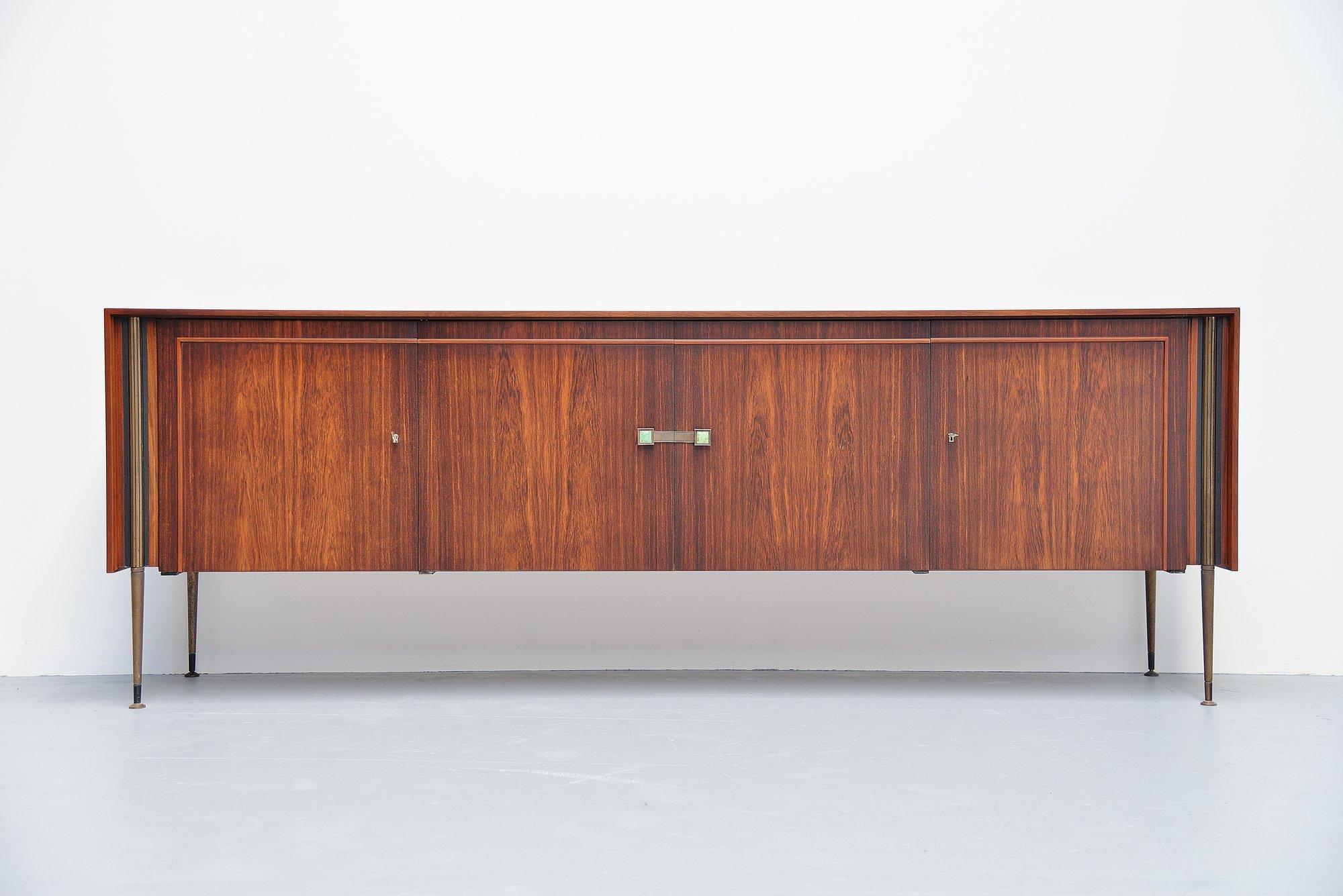 Superb quality sideboard in rosewood with brass details, Holland 1950. This high quality finished sideboard is probably made by a small furniture company in Holland and refined into perfection. This sideboard has brass legs and brass grips with
