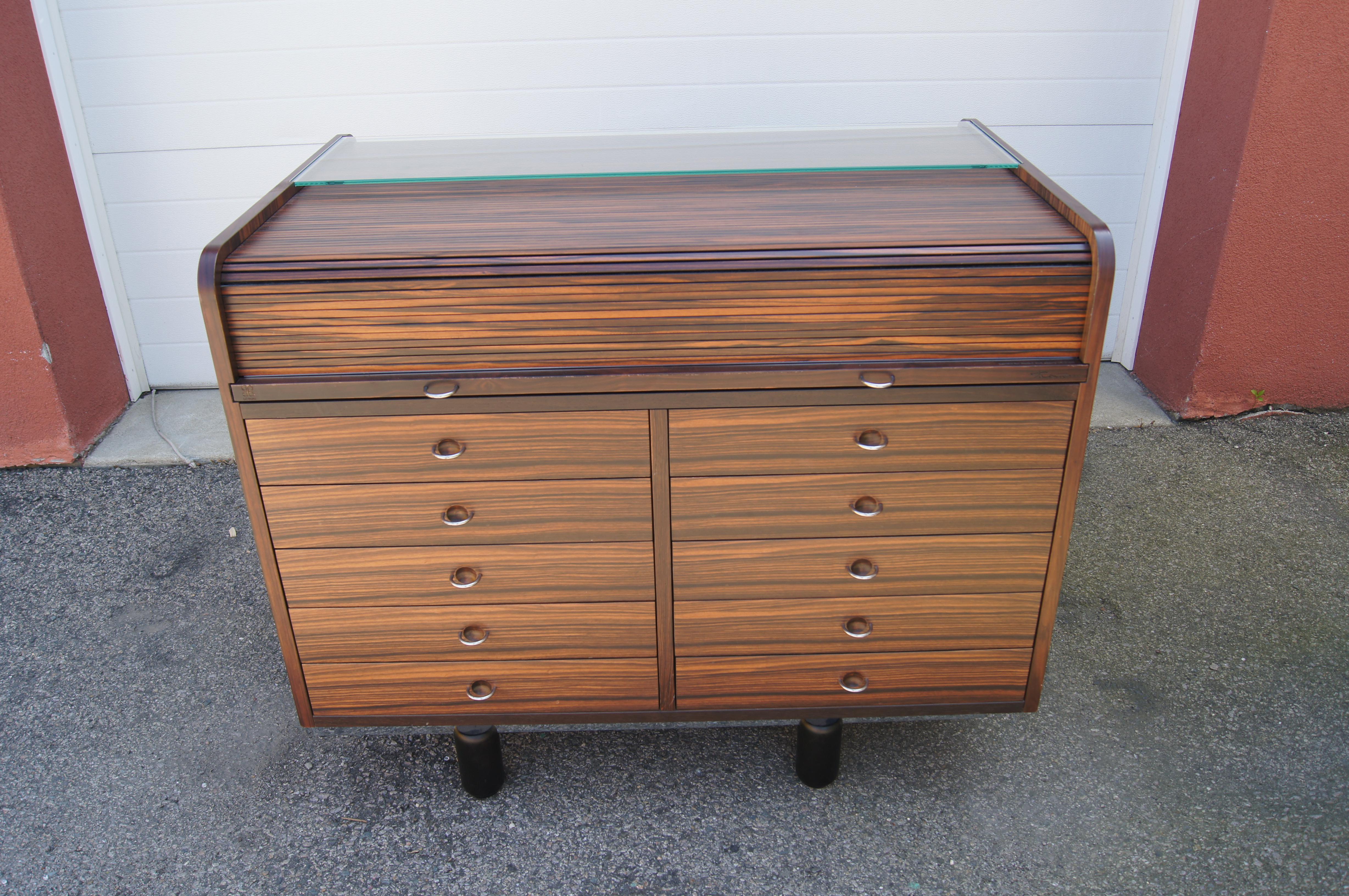 Gianfranco Frattini designed this gorgeous rosewood rolltop desk, model 804, for Bernini in the early 1960s. What appears to be a compact chest of ten drawers with chrome pulls transforms into a desk when the concealed leather-covered top is pulled