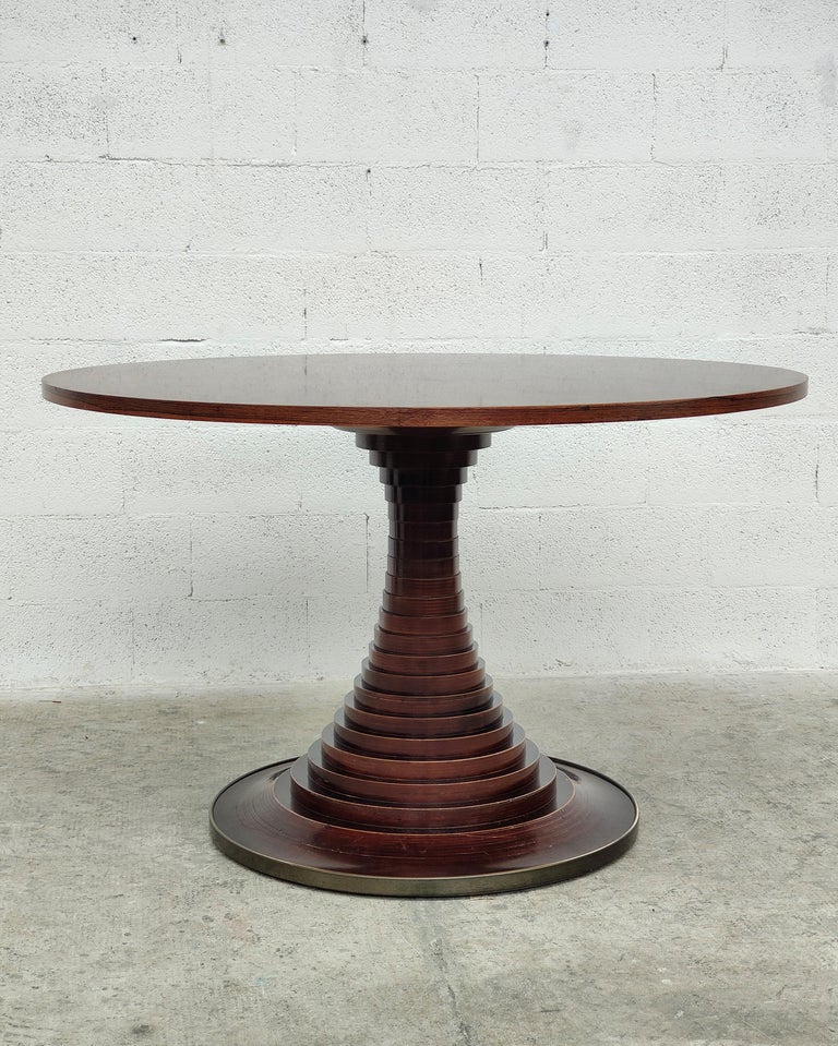 Rosewood circular dining table designed by Carlo de Carli for Sormani 1960s.
The beautiful top stands on a striking base made of solid wooden discs, with a circular brass trim detail. 
Dimensions: diameter 125 cm - height 78 cm.
 