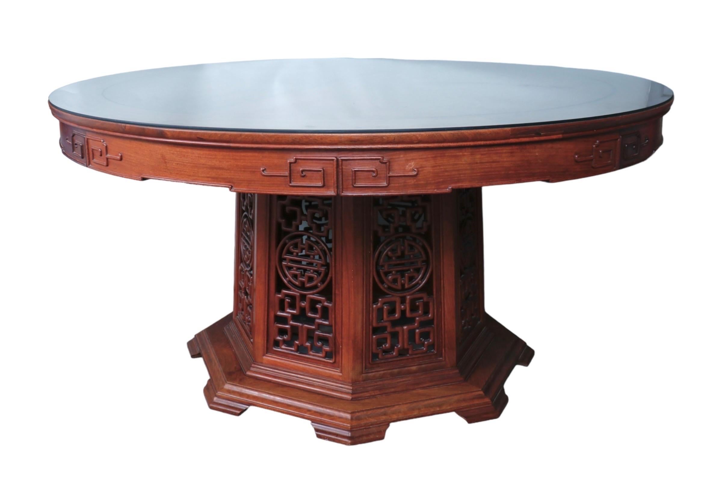 Table de salle à manger ronde de style Ming avec une base octogonale sculptée, en bois de rose. La jupe de la table est décorée de rinceaux quadrillés et, en dessous, la base du piédestal est finement sculptée de panneaux ajourés. Au centre de