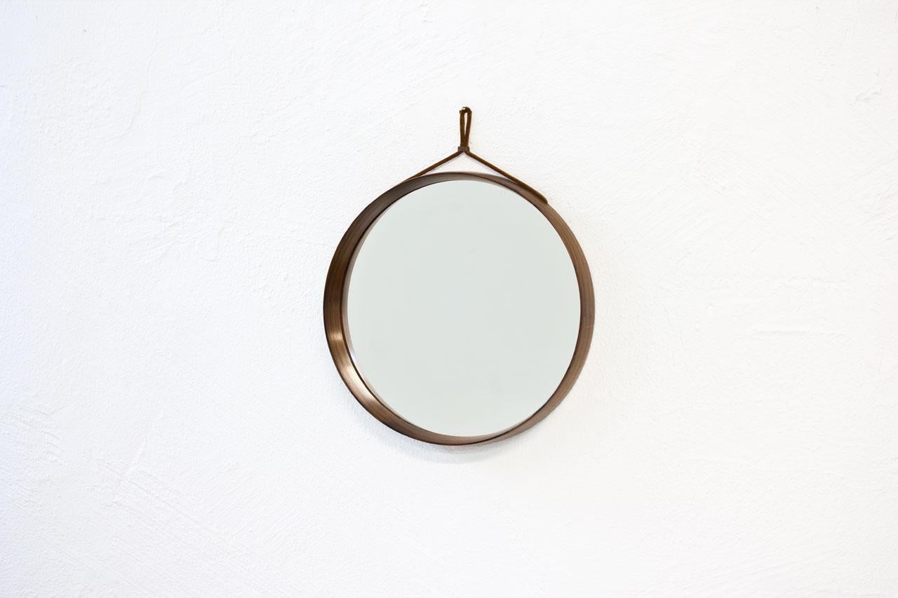 Rosewood round wall mirror designed by Uno & Östen Kristiansson for their own
company Luxus at Vittsjö, Sweden during the 1950s. Made from rosewood with leather strap. Signed on the back.