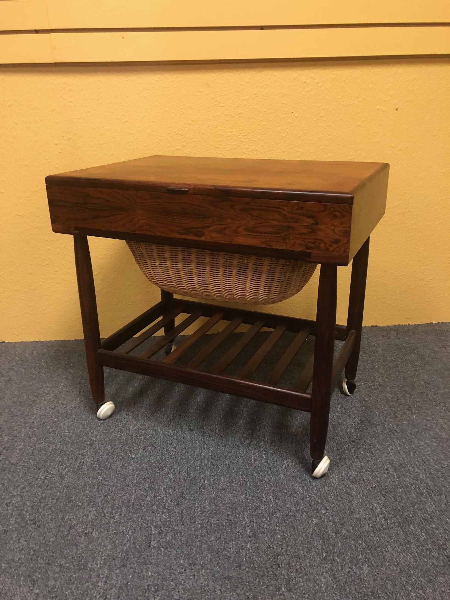 Wonderful midcentury rosewood sewing table / cart by Ejvind Johansson for Vitre of Denmark, circa 1960s. The stylish design features a rosewood handle to access interior compartmentalized storage, while a lower shelf allows access to built in