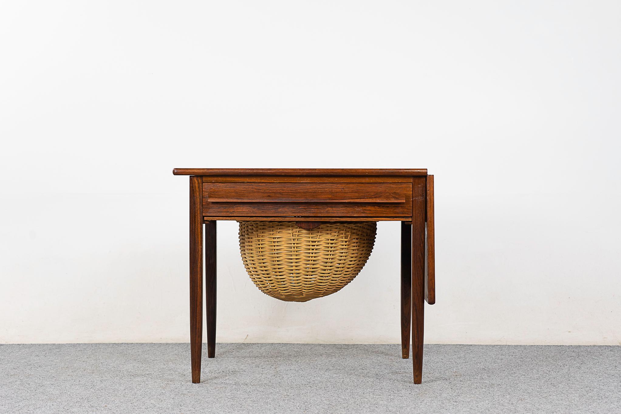 Rosewood sewing table by Johannes Andersen, circa 1960's. Sweet sewing table, can double as a perfect end table or accent piece. Handy drawer with fitted interior, original woven basket sides out for sleek storage. 

Unrestored item, some marks