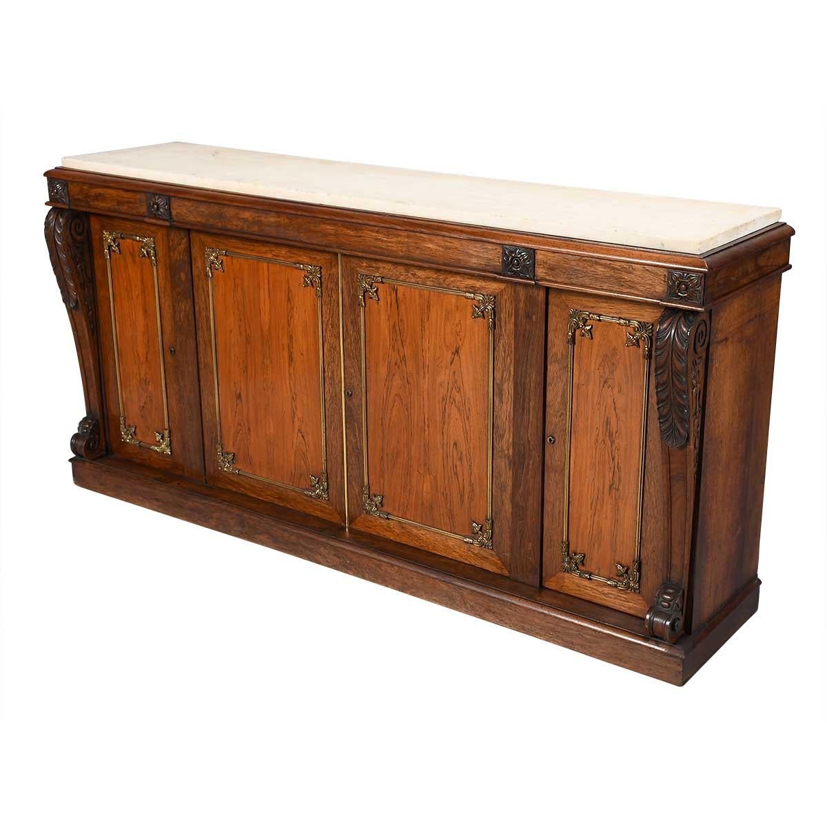 Armoire en bois de rose avec des montures en bronze doré sur les portes, un plateau en marbre et des pilastres sculptés à chaque extrémité, surmontés de rosettes sculptées. Les portes peuvent être grillagées ou revêtues de tissu à l'origine.