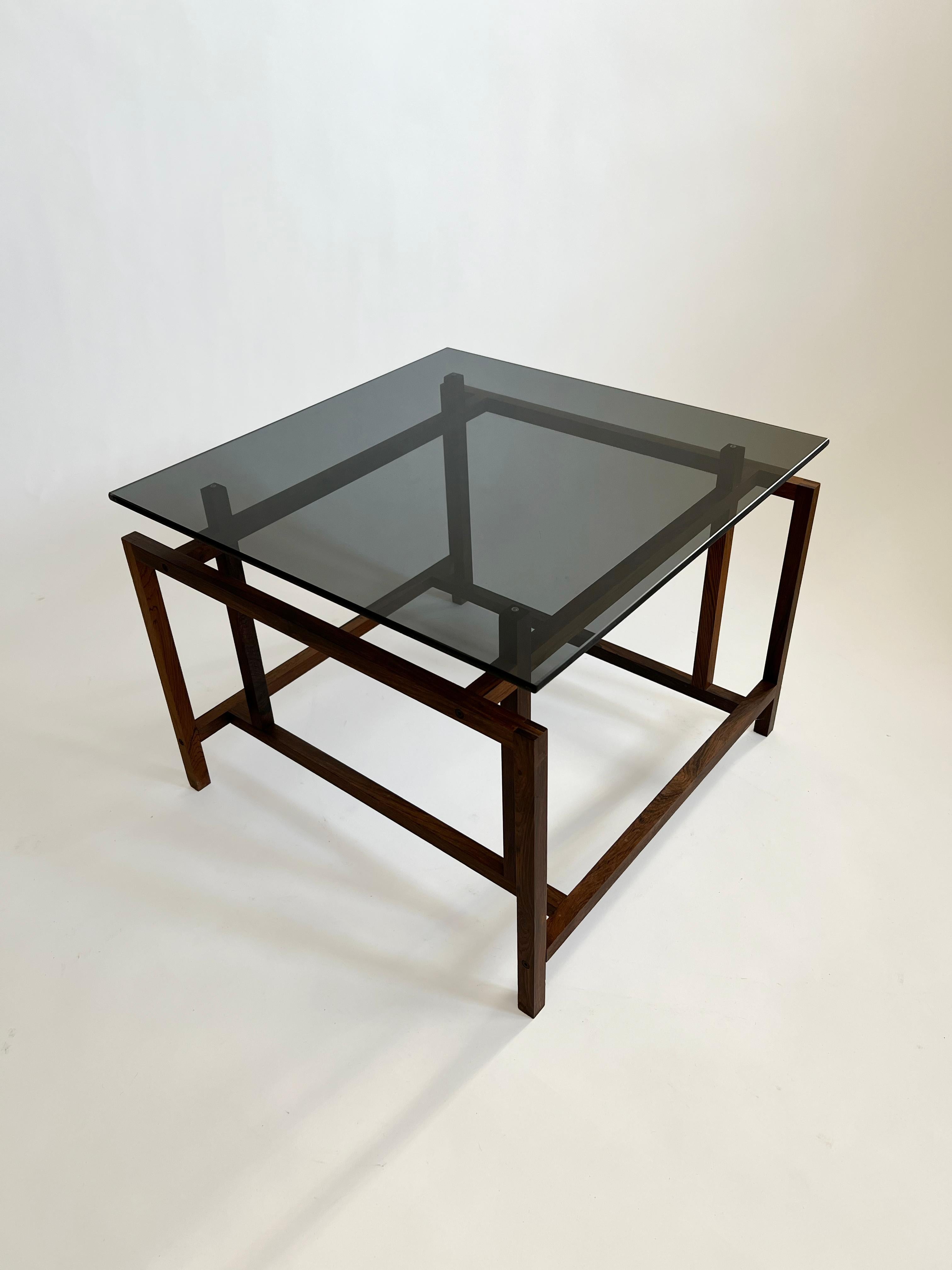 Rosewood and glass side table by Henning Norgaard for Komfort, made in Denmark in the 60s. The glass is 6mm thick and held in place with wood pins that fit into recesses in the glass.