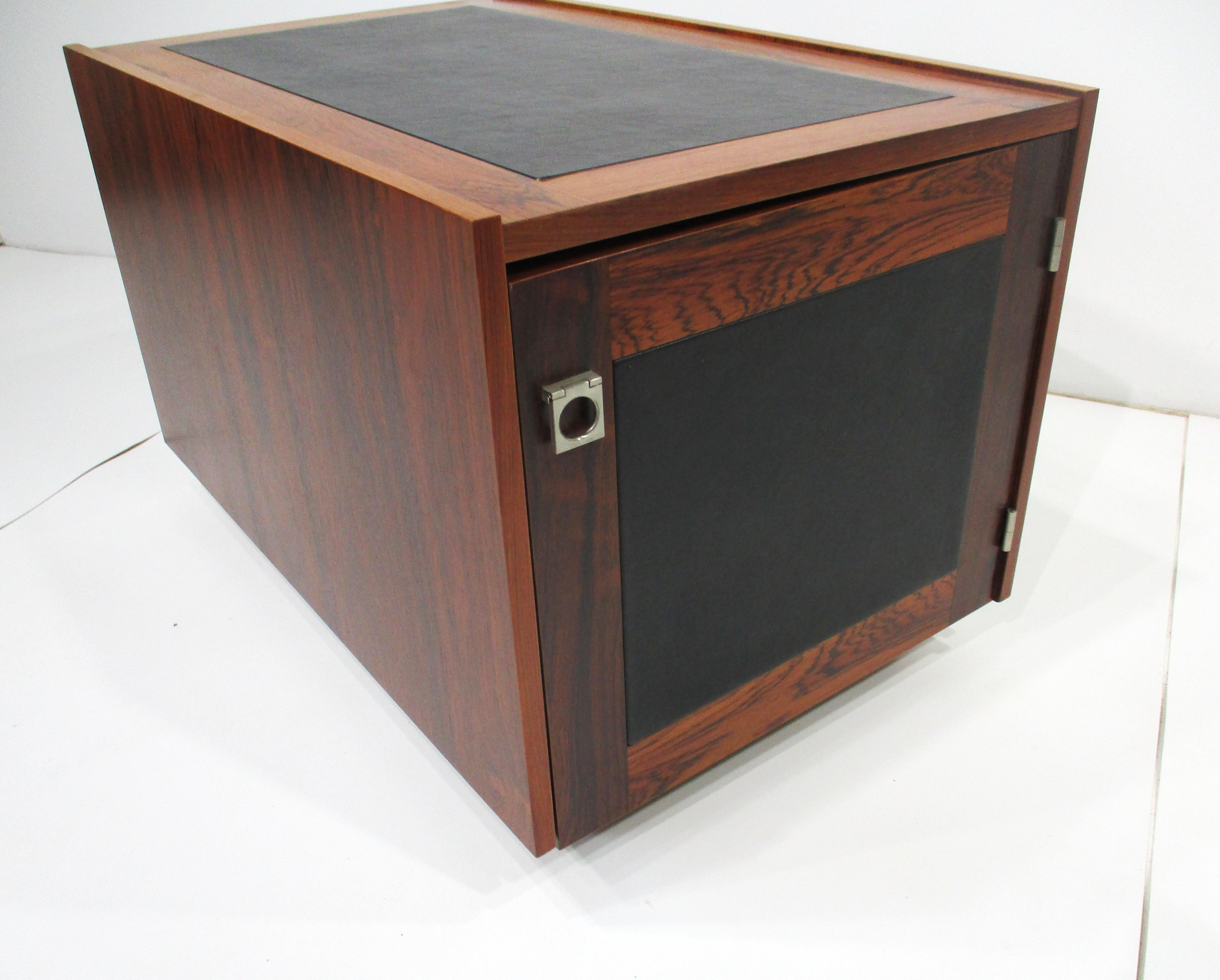 A exceptionally stunning Brazilian rosewood side table storage cube with black leatherette inserted top . The front has a door with chrome pull having storage inside and to the backside an open storage bin , the perfect piece for a smaller space or
